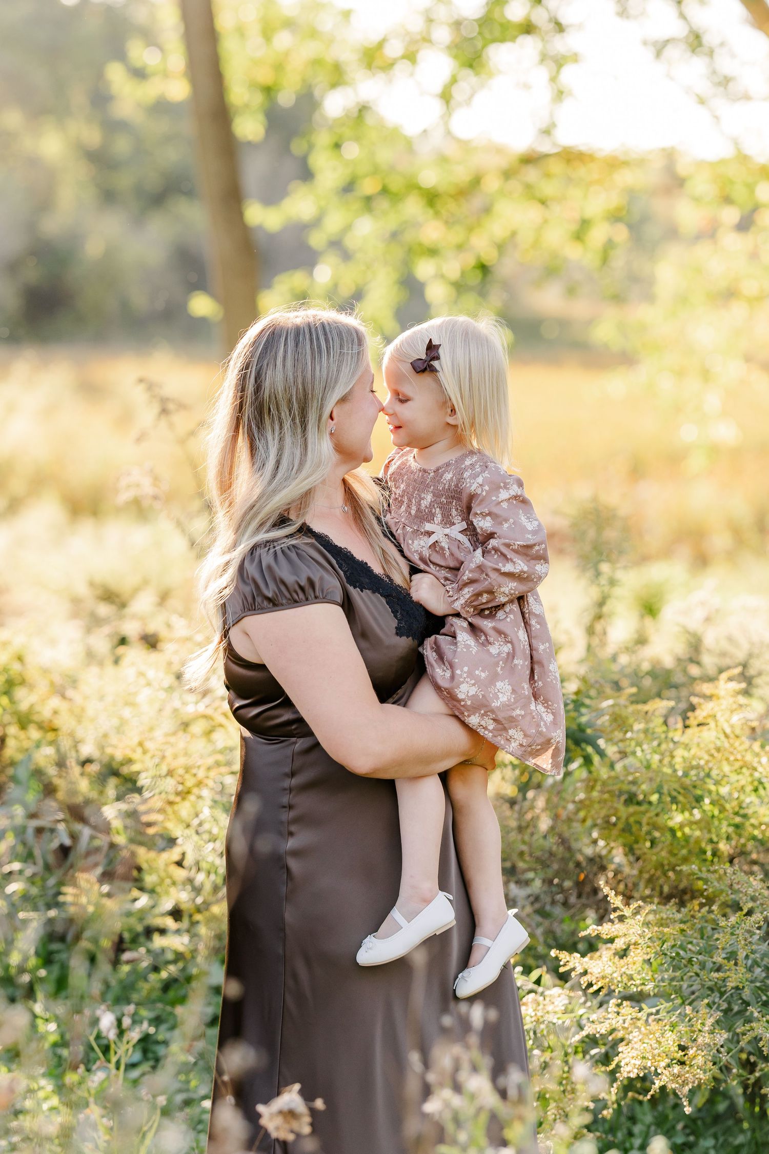 Mom holding her youngest daughter close in golden afternoon light in their St. Charles, IL backyard.
