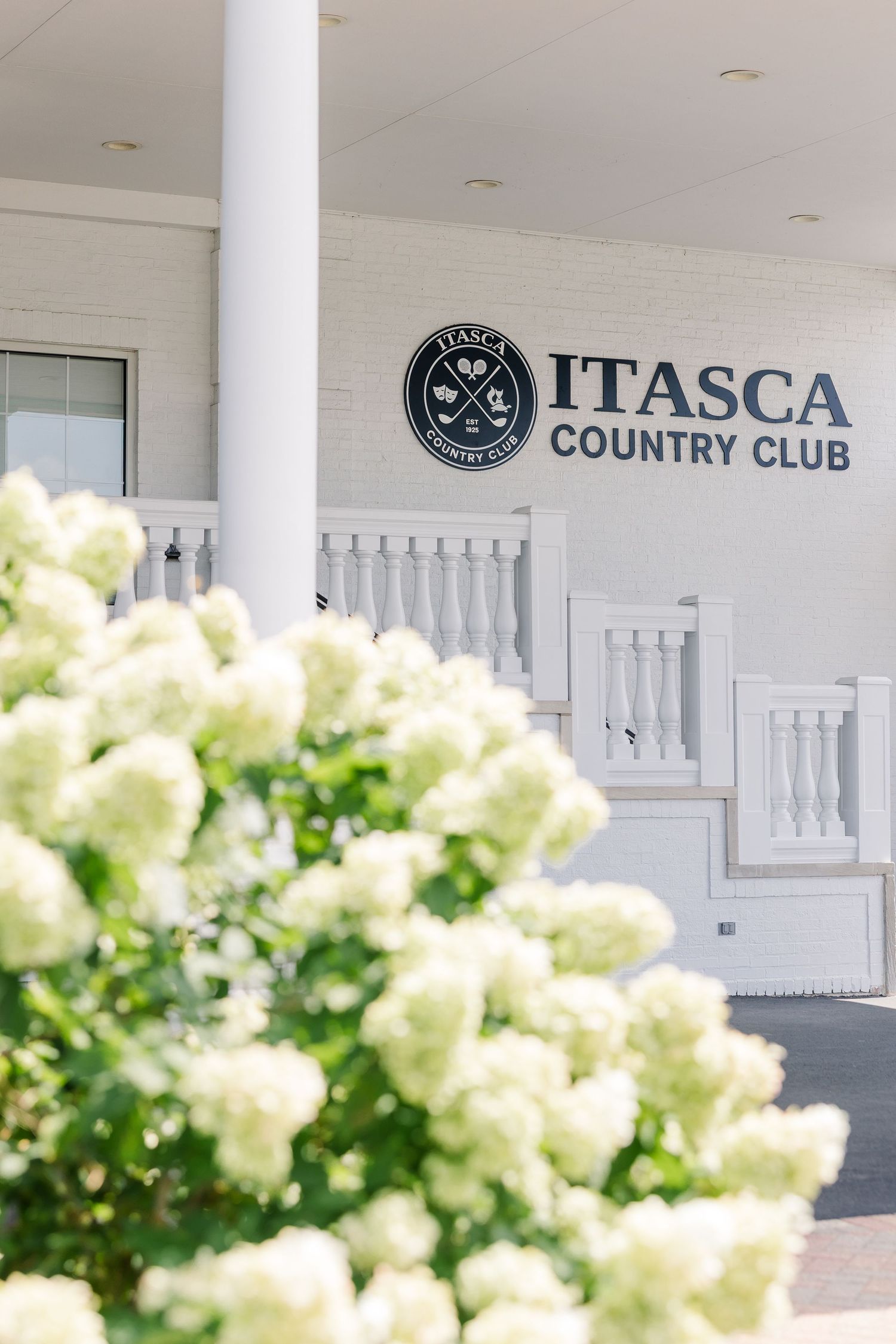 Itasca Country Club sign surrounded by white hydrangea blooms