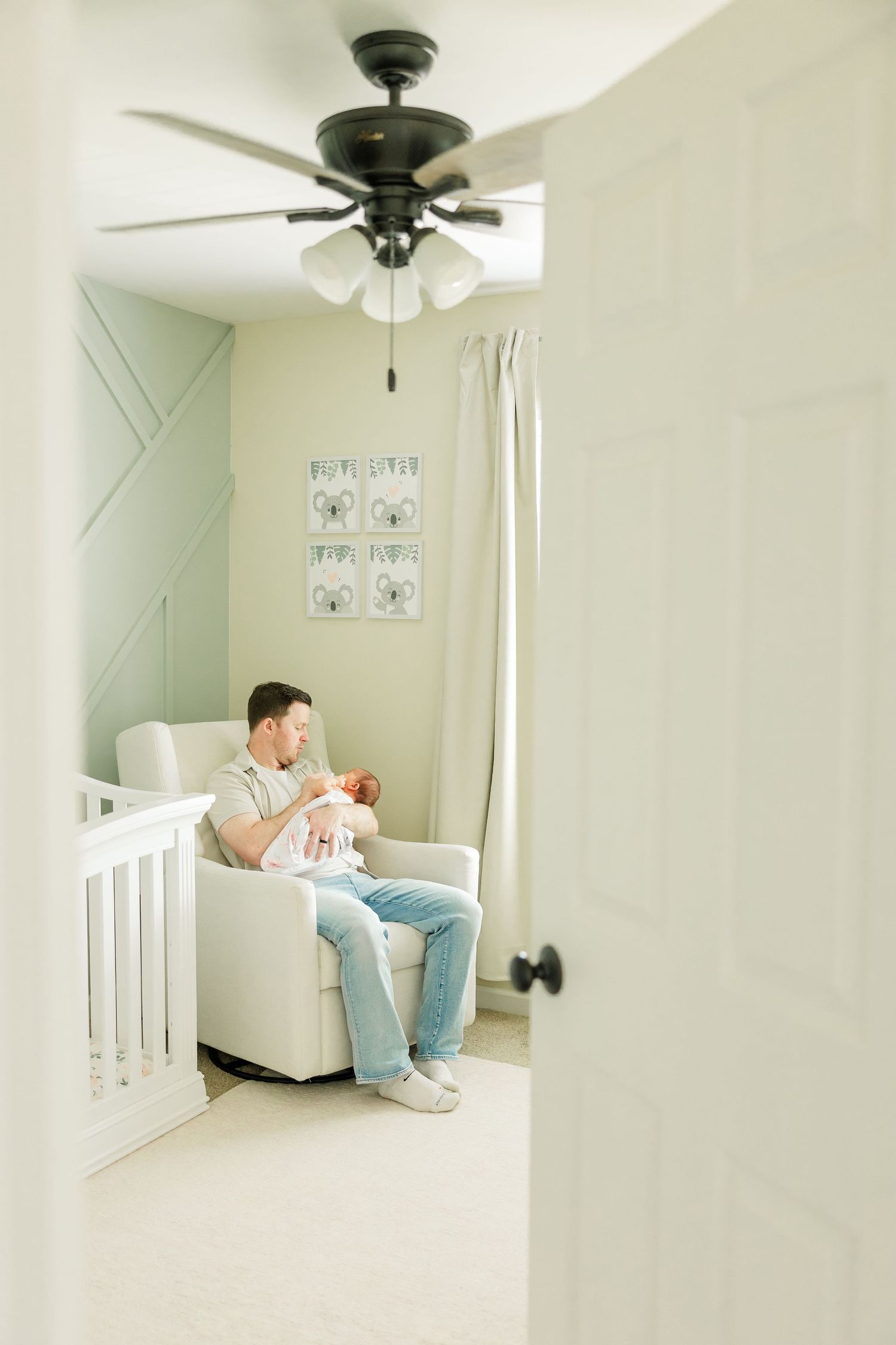 Dad holding newborn baby girl in the nursery during a peaceful in-home newborn session in Huntley IL