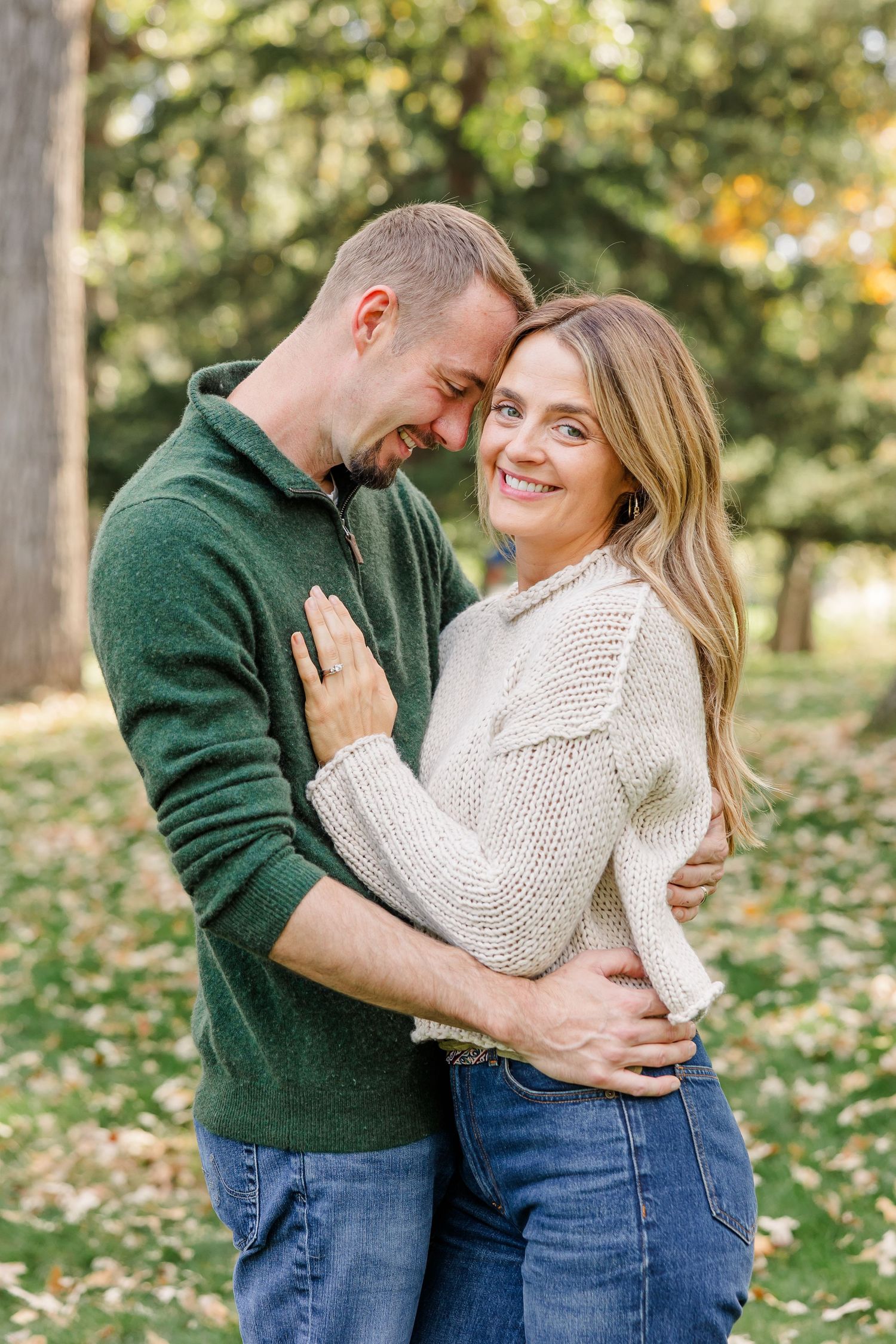 Happy couple embracing and smiling together outdoors in a green autumn park.
