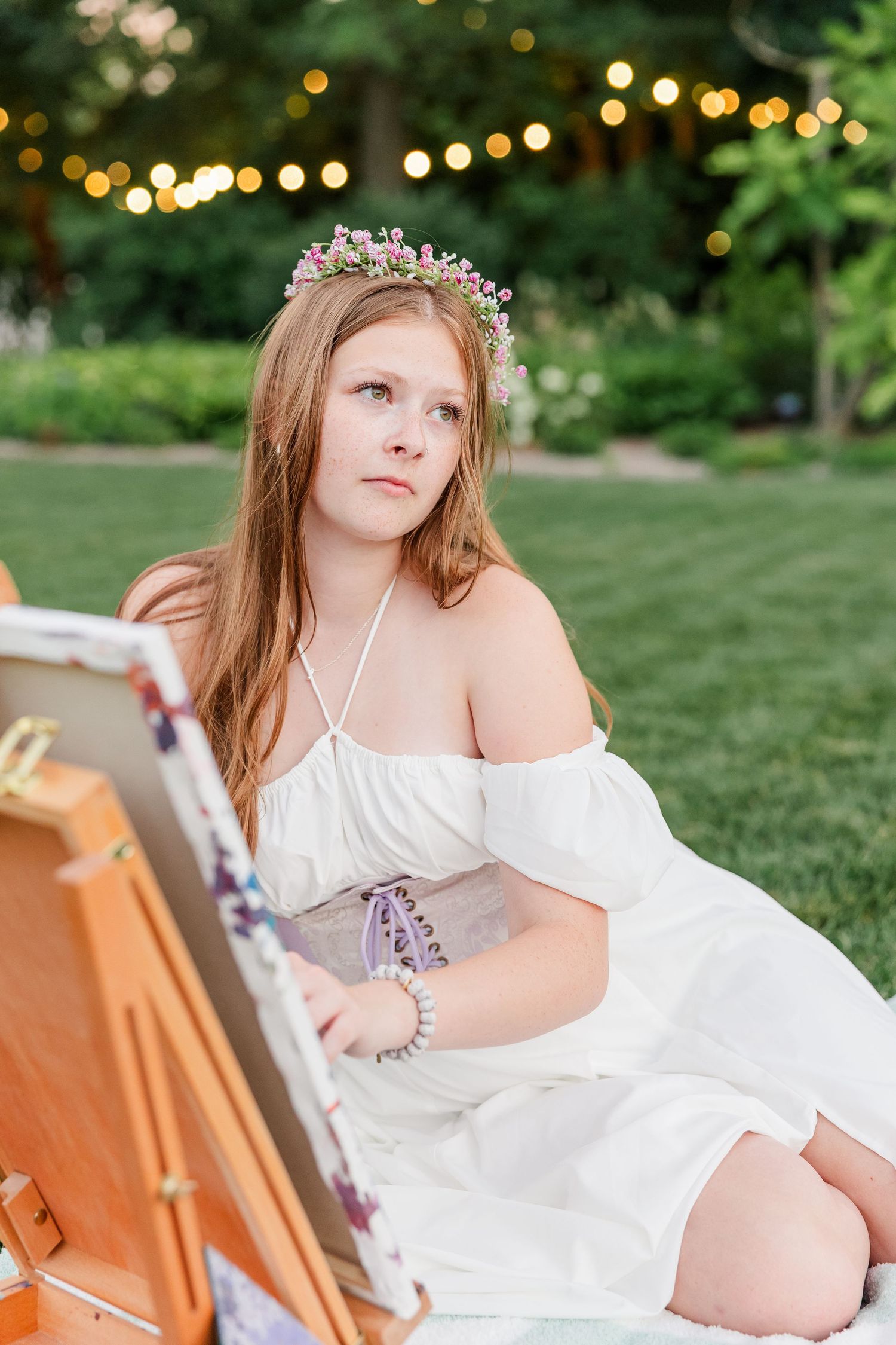 Artistic senior portrait of Samantha wearing a flower crown and painting beside her easel at Cantigny Park.