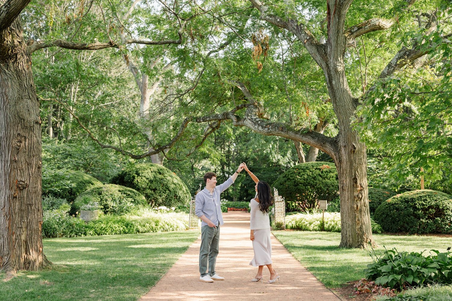 Jack twirls Alysia beneath the trees during their just-engaged portraits.