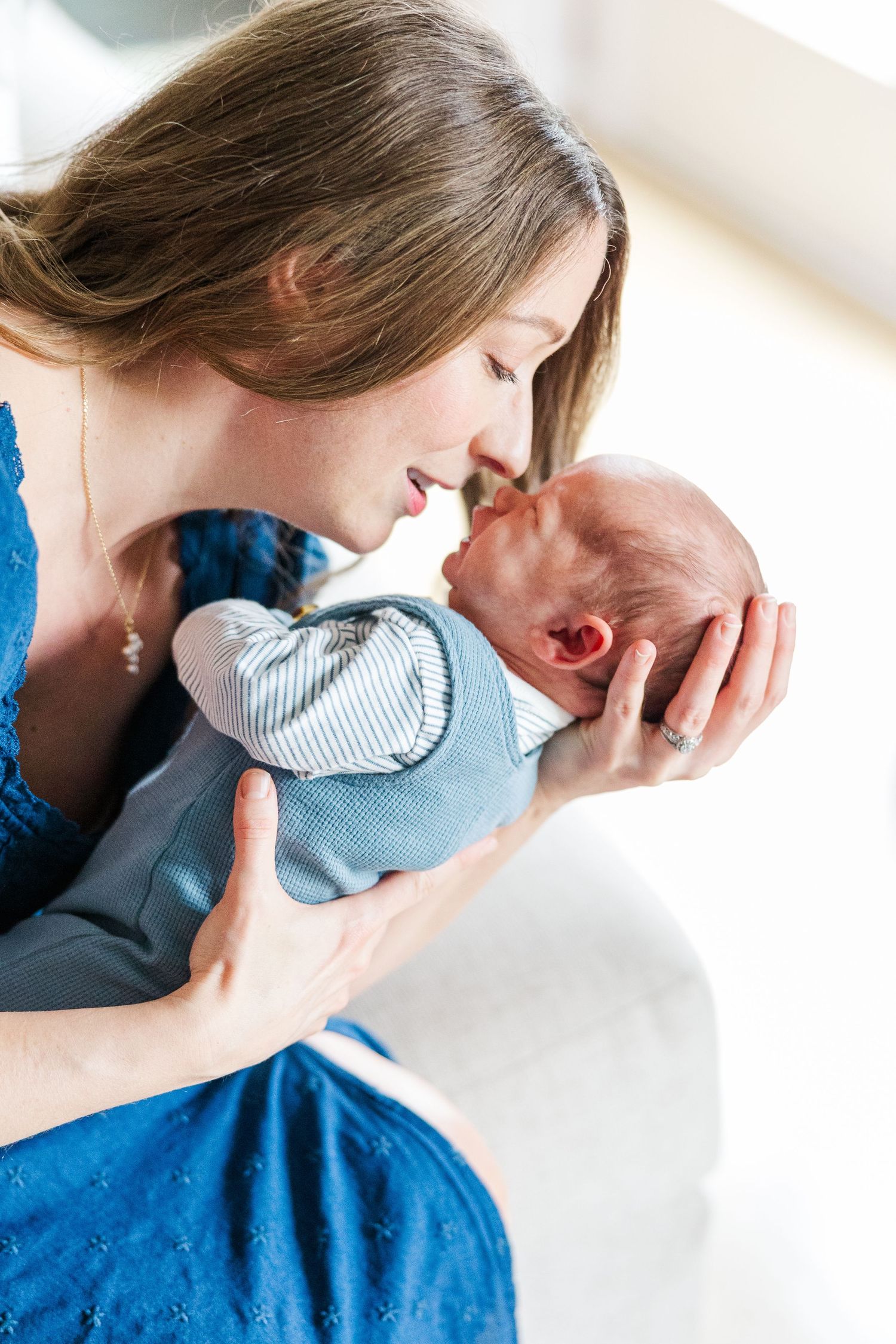 Mother kissing newborn son during bright in-home lifestyle newborn session in Crystal Lake, Illinois