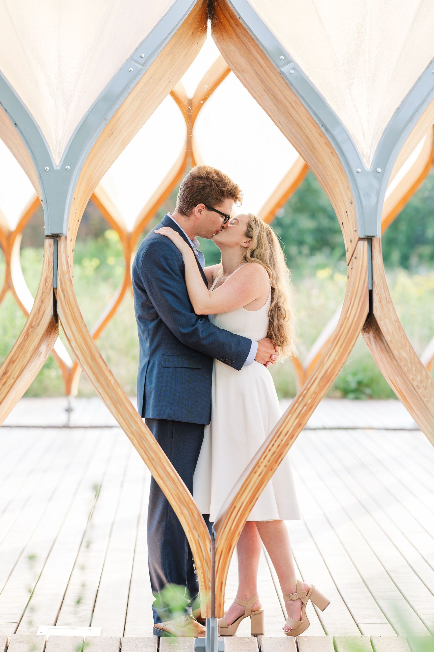 Elizabeth and Joe standing under the Honeycomb Pavilion in Lincoln Park, Chicago, kissing each other