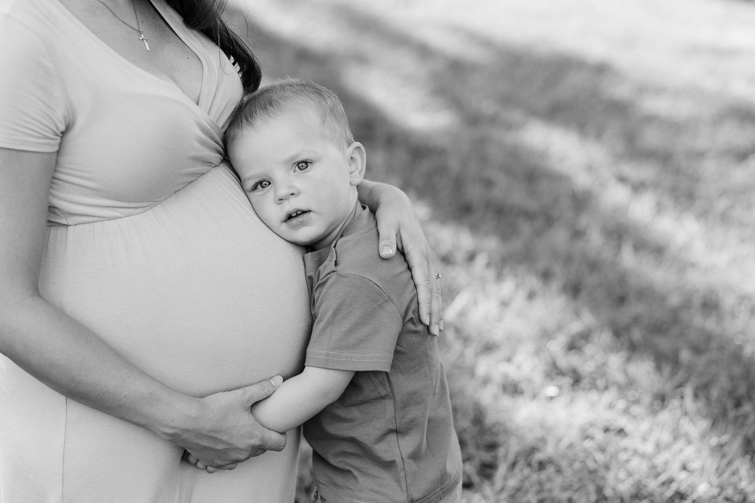 Black and white maternity photos showing gentle moments between parents and children outdoors in nature.
