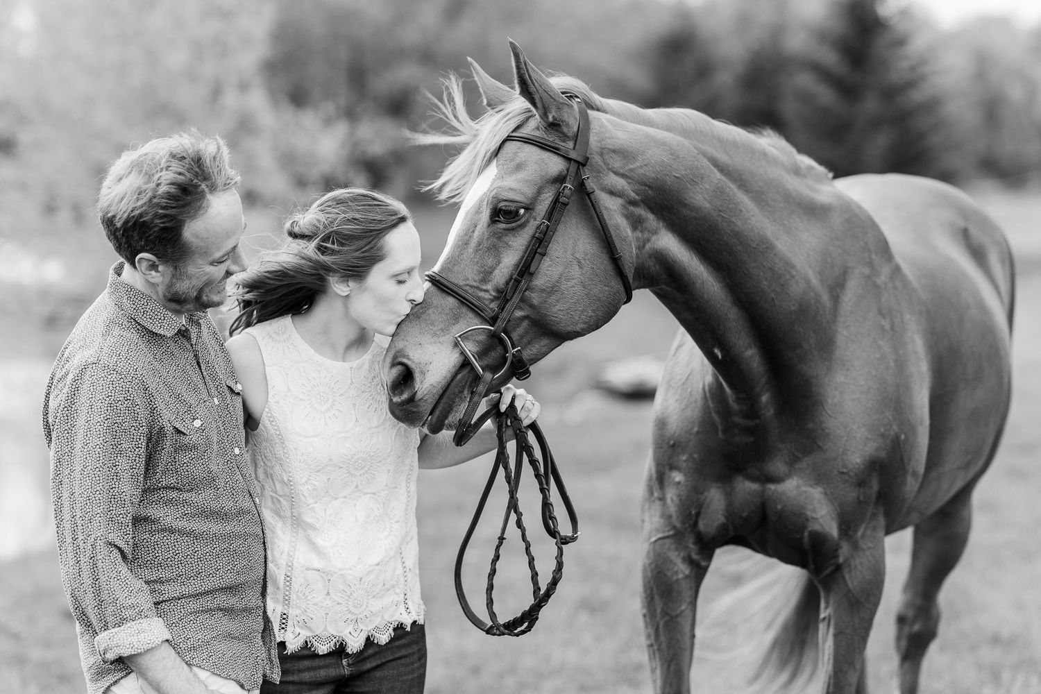 A vintage black and white photo of a couple with their horse on a farm.