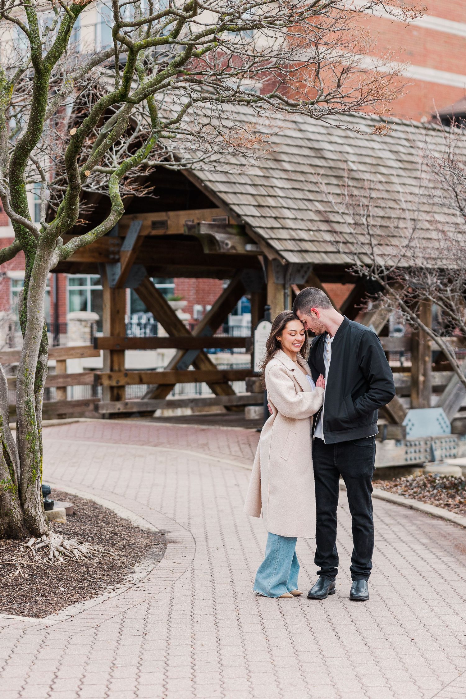A tender embrace shared near a rustic pavilion on a winding garden path.