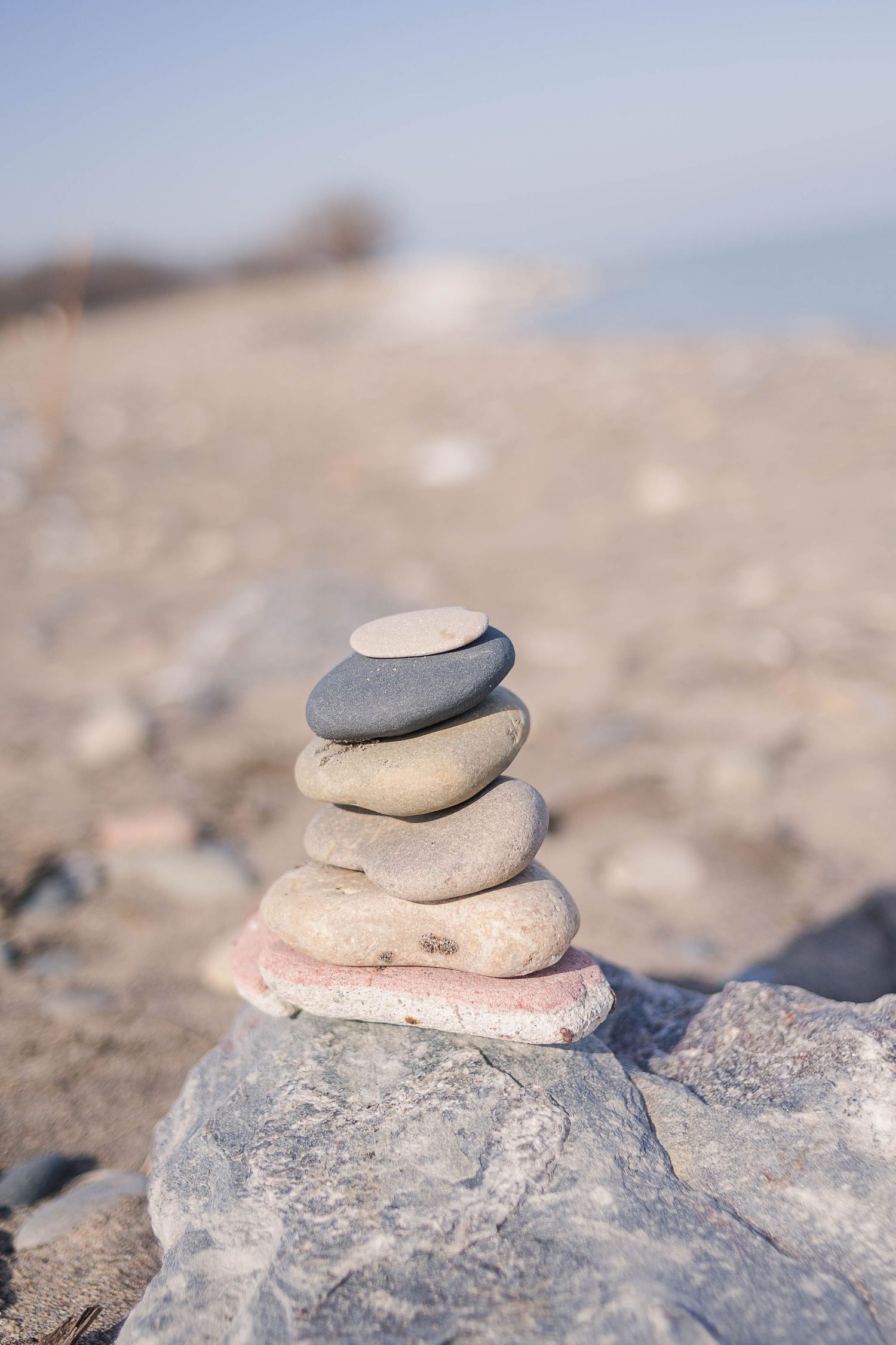 Stack of balanced smooth stones on rocky beach against blurred background.