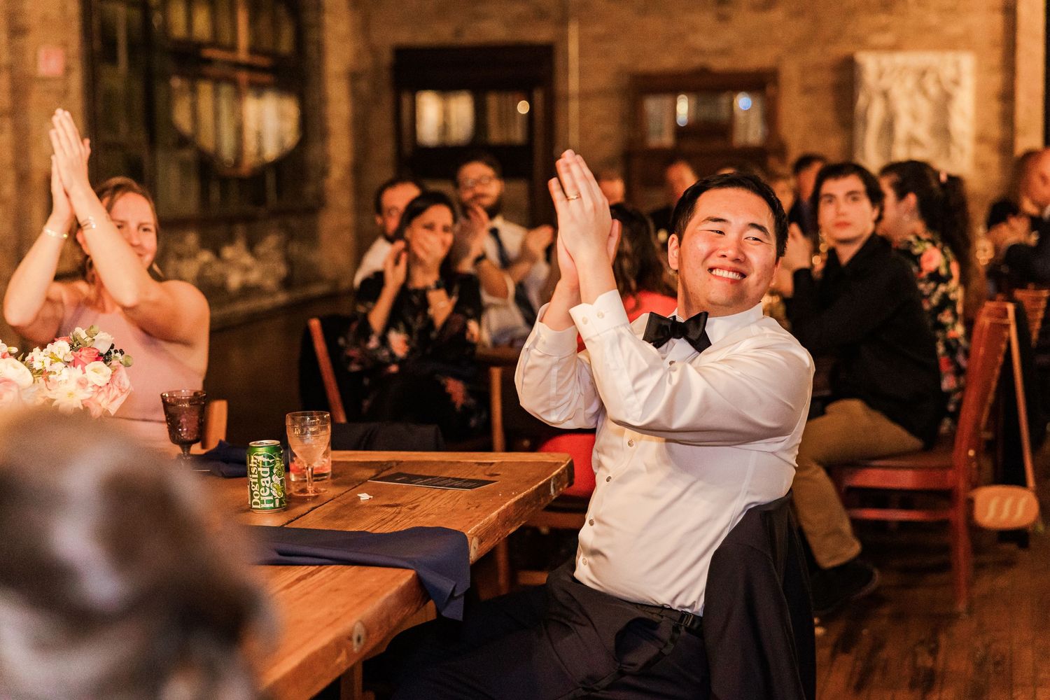 Wedding guests applaud enthusiastically during a reception celebration.
