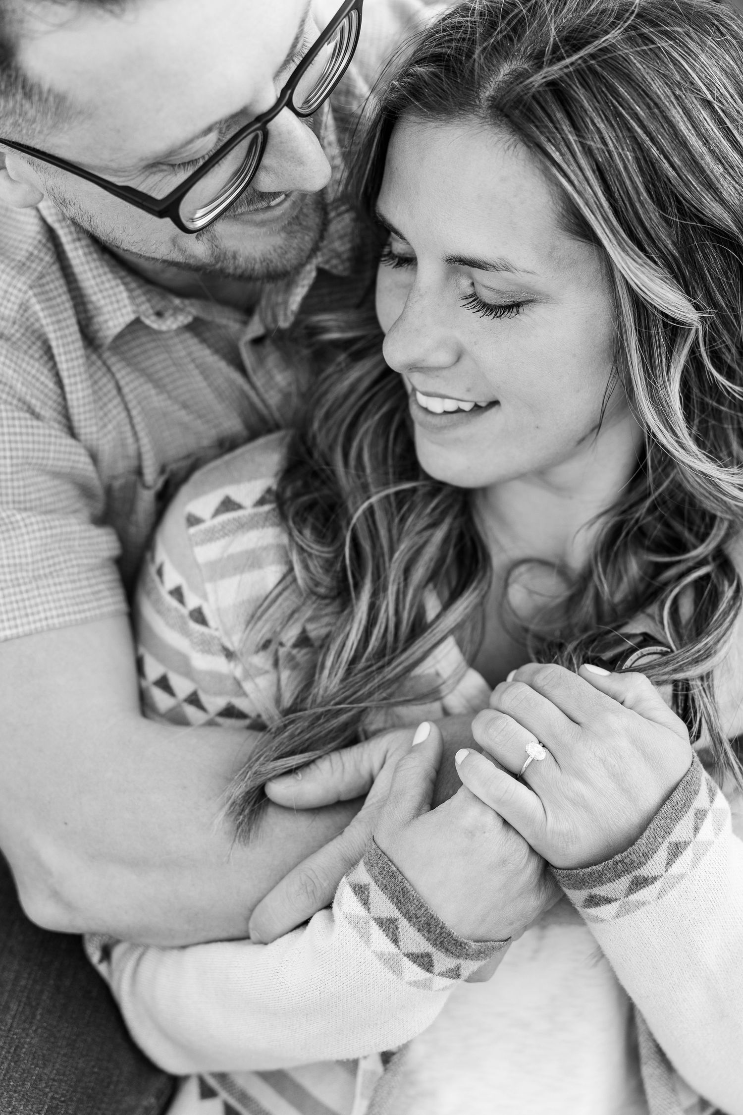 Black and white engagement photo of a couple cuddling with their dog