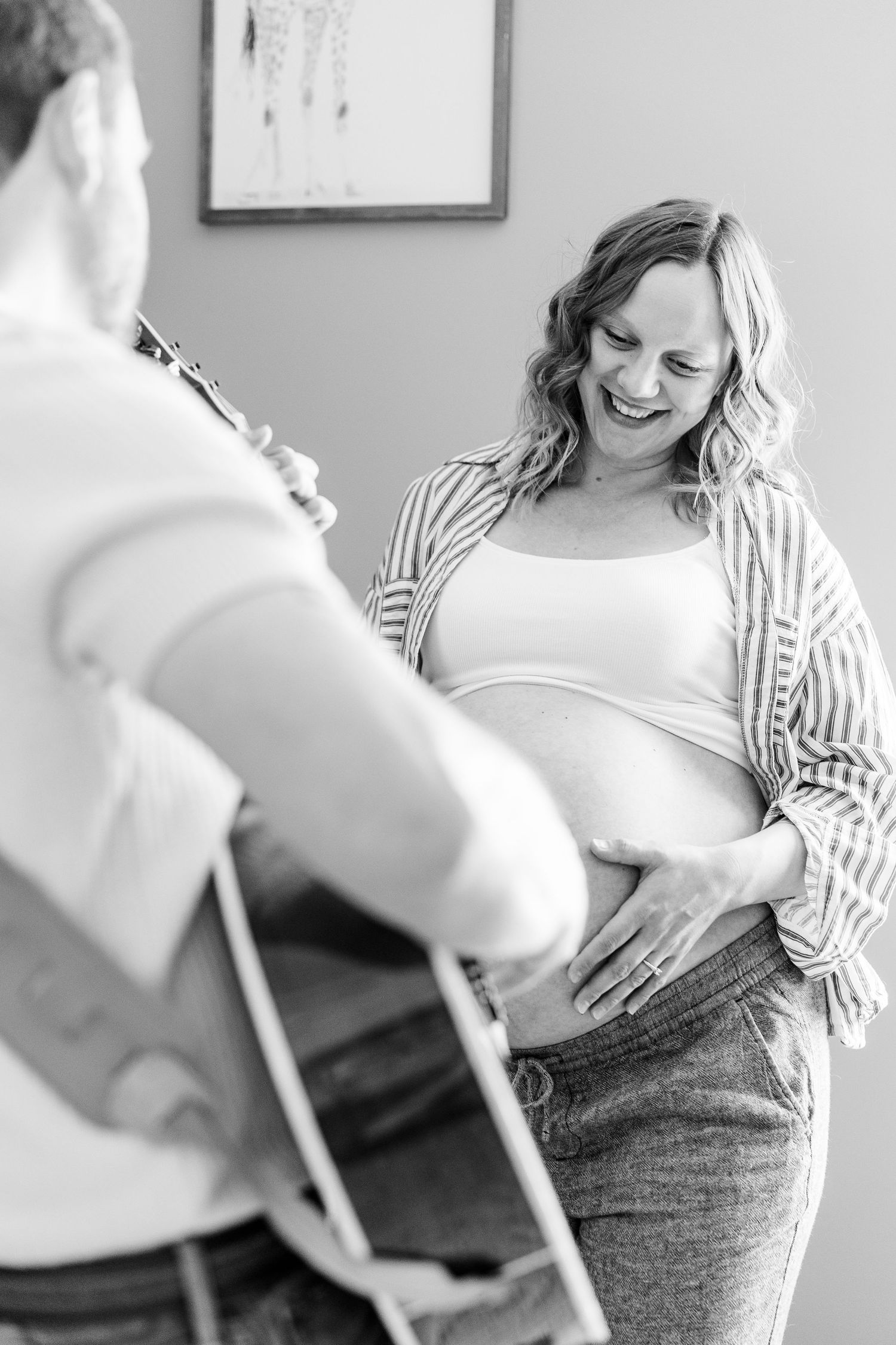 Black and white in-home maternity photo with father playing guitar for mother and babies in Crystal Lake, Illinois.