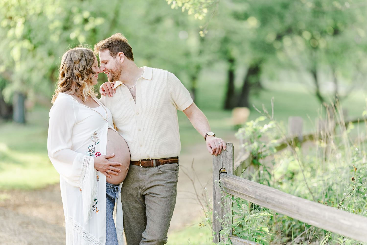 Expecting parents holding baby bump during a soft golden hour maternity session at Veterans Acres.