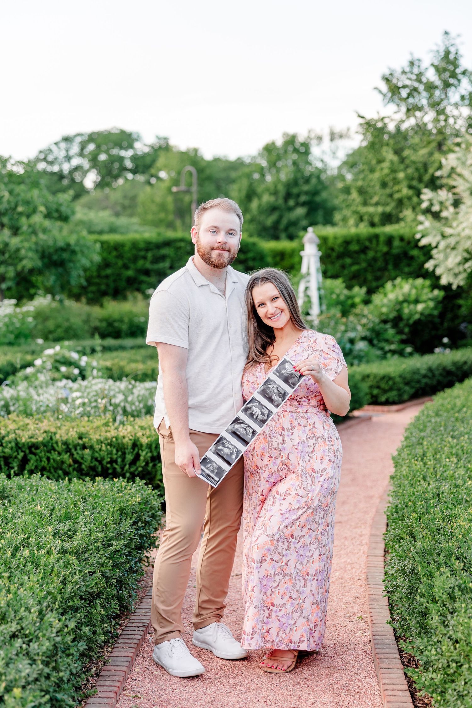 Parents-to-be standing together with ultrasound photos during a Cantigny maternity session in Wheaton Illinois