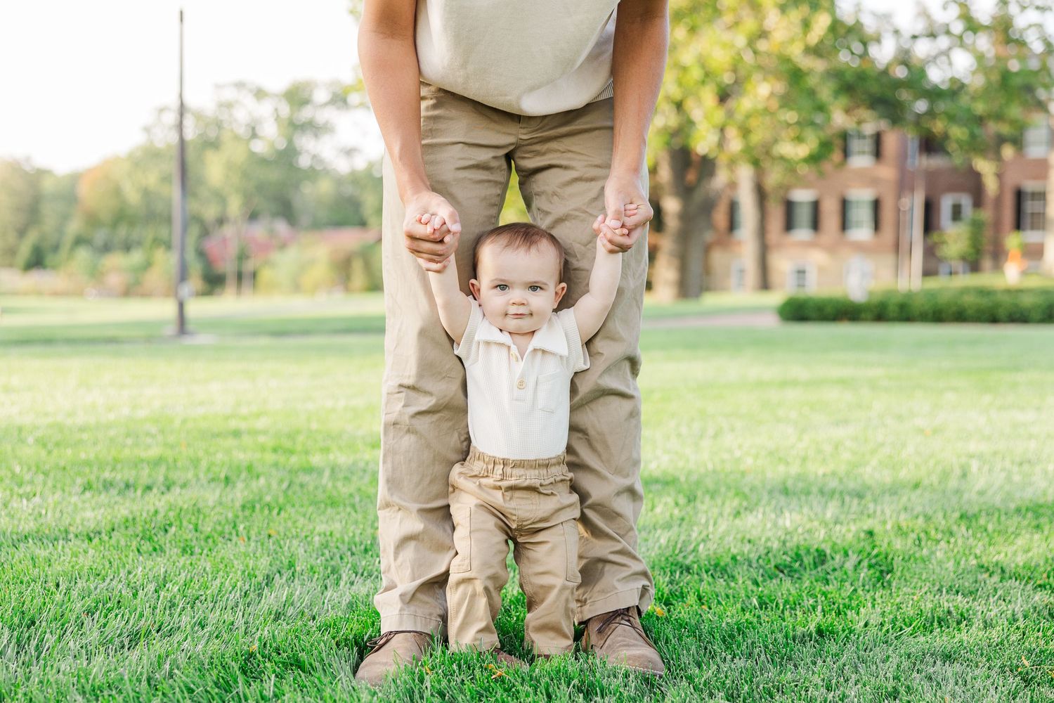 Baby holding parents’ hands learning to walk during a family portrait session at Cantigny Park Wheaton IL.