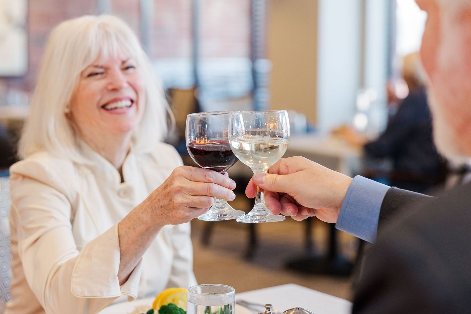 Beacon Hill senior living branding photo in Lombard, Illinois featuring residents toasting over dinner