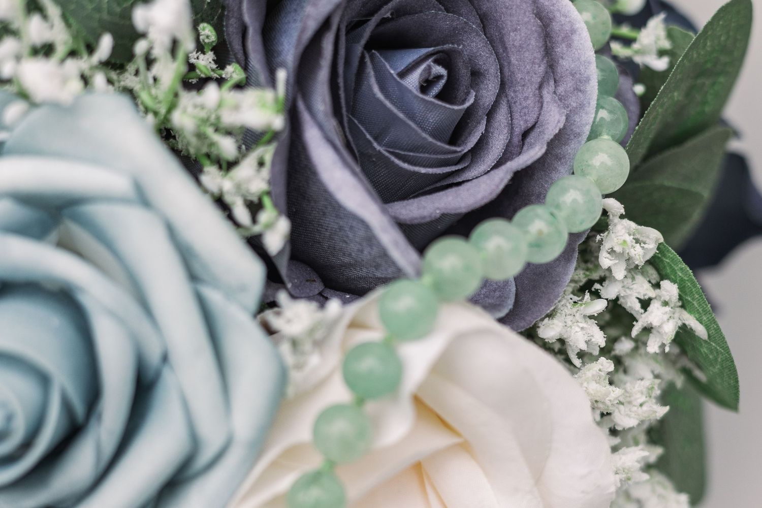 Elegant bouquet featuring blue and ivory roses with baby's breath and green accents.