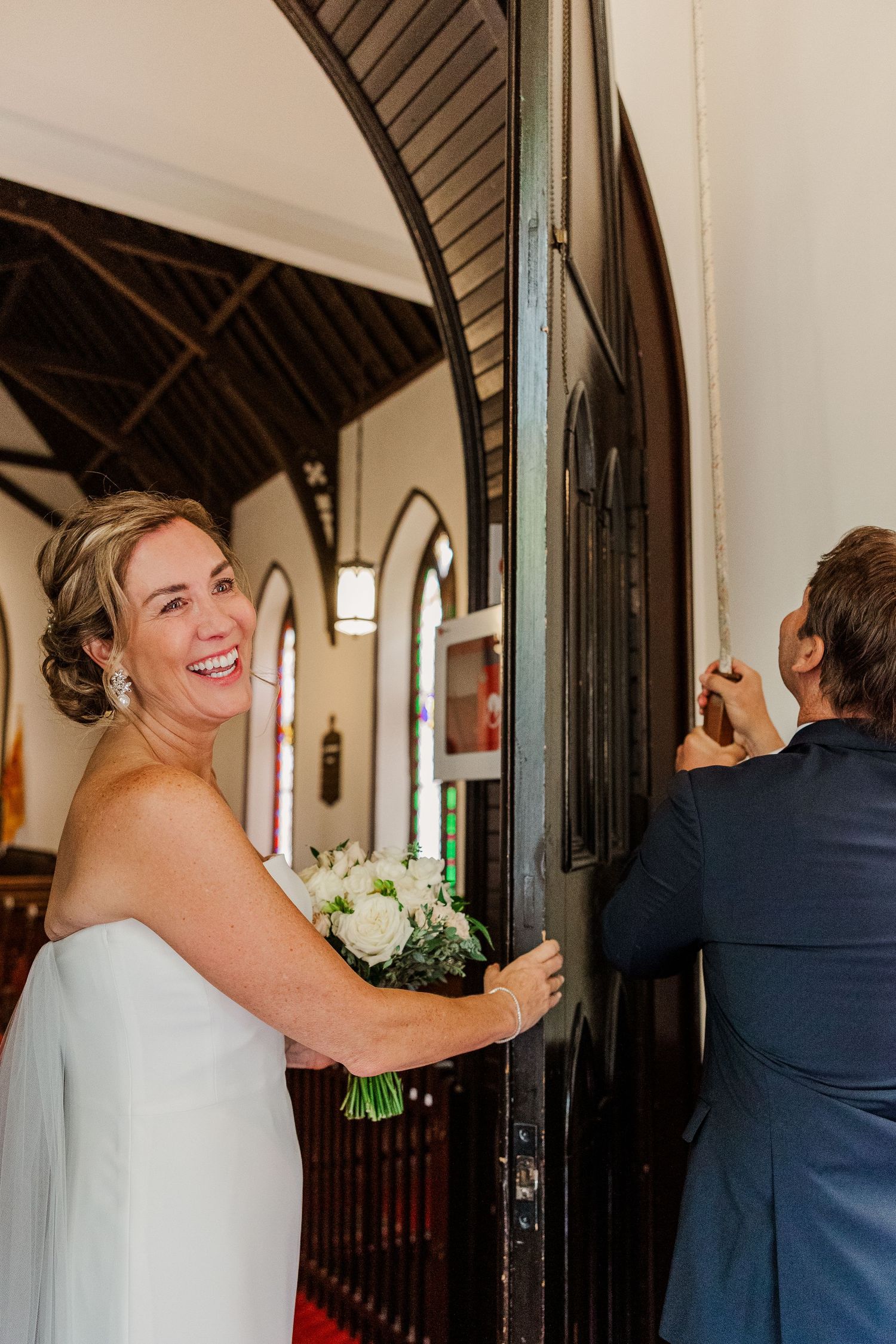 A joyful moment captured as a couple enters a church doorway on their wedding day.