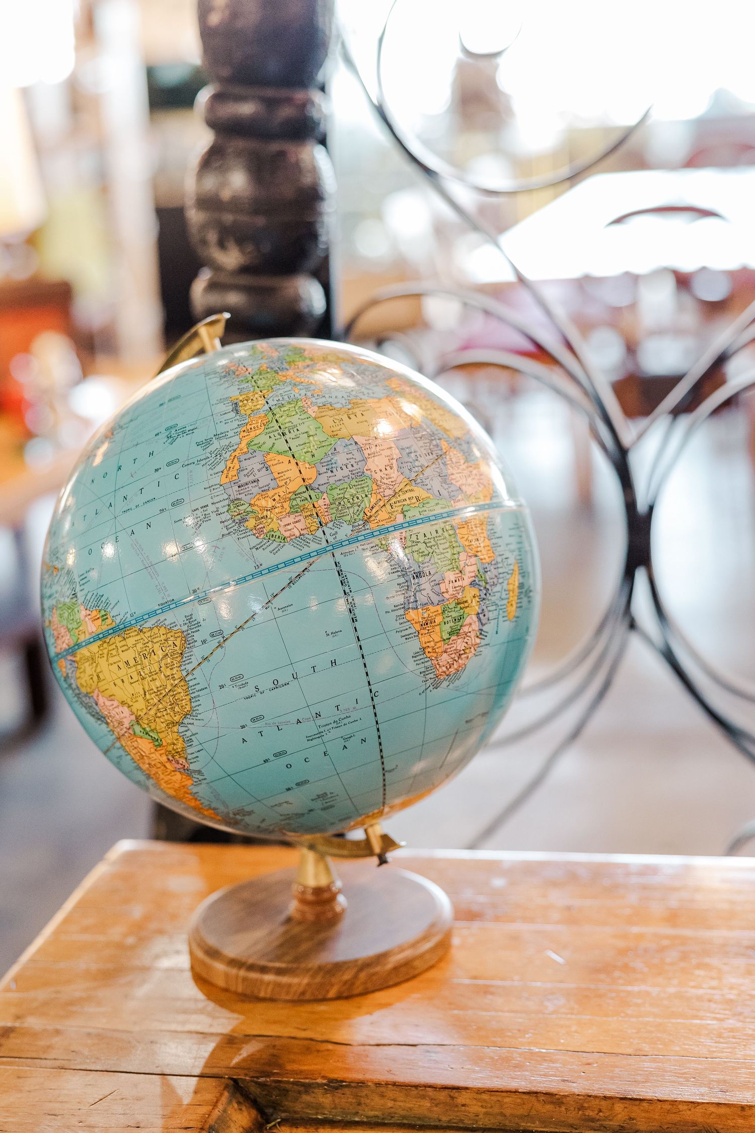 Vintage blue globe on wooden stand displayed on table with decorative background.