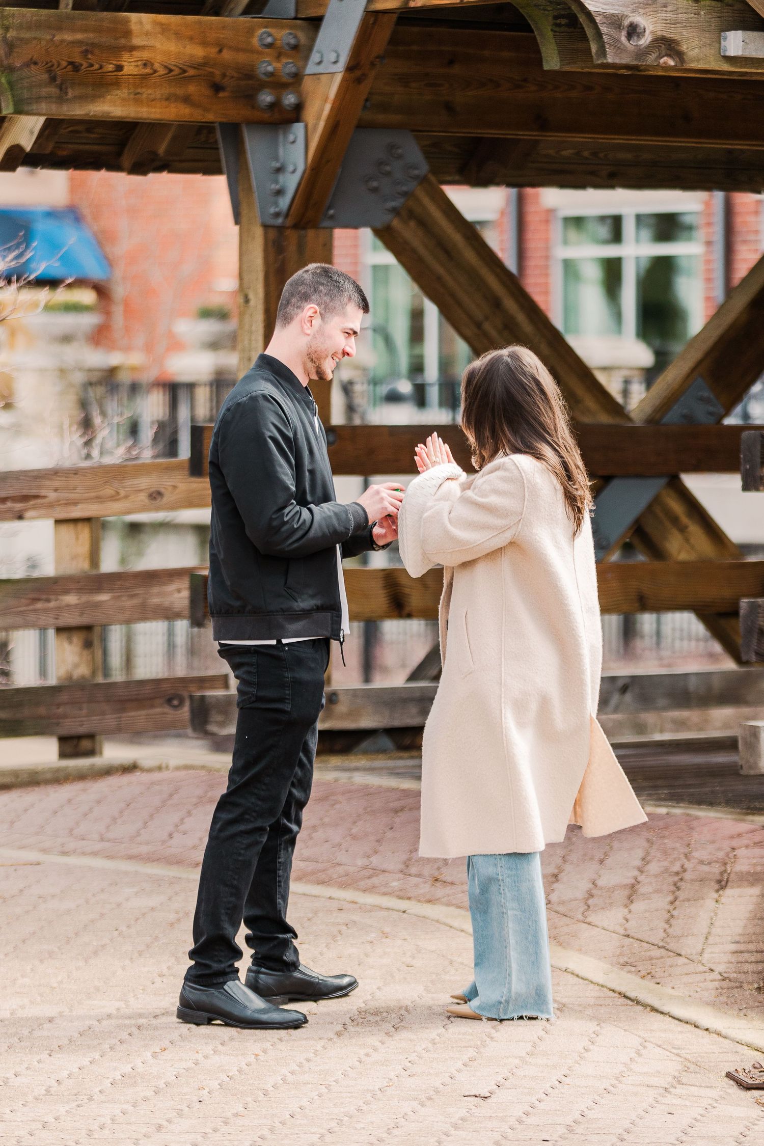 A couple reacts emotionally while exchanging rings under a wooden pavilion.