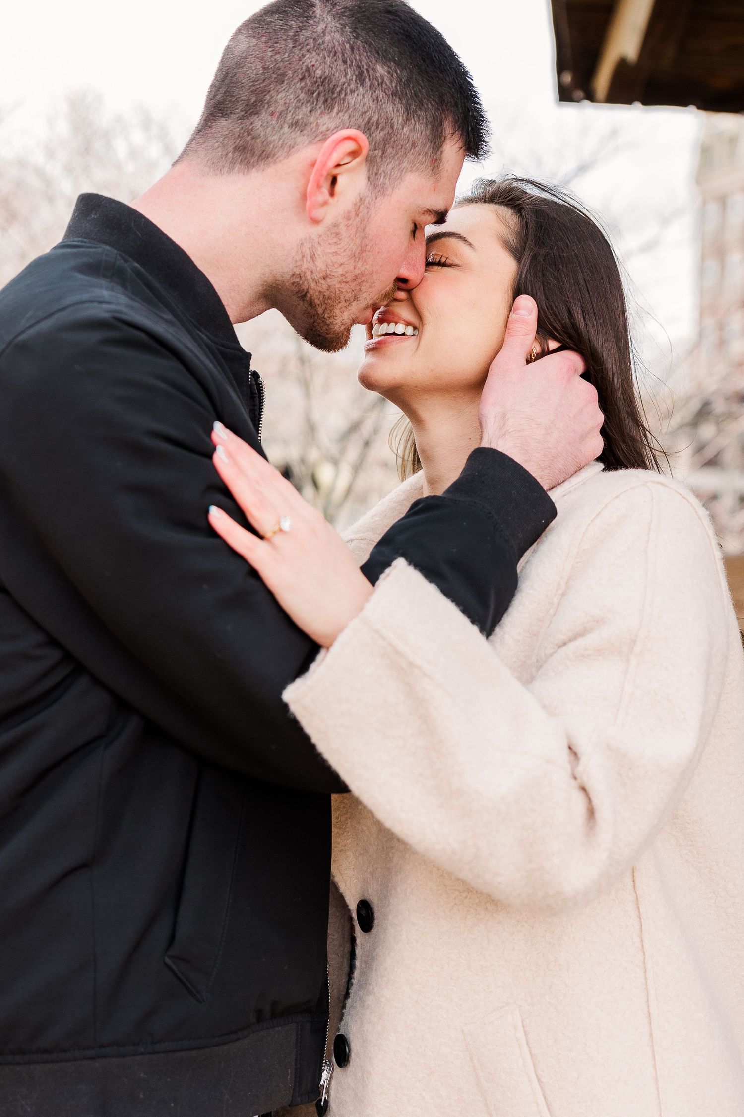 A romantic couple shares a tender moment wearing winter coats outdoors.