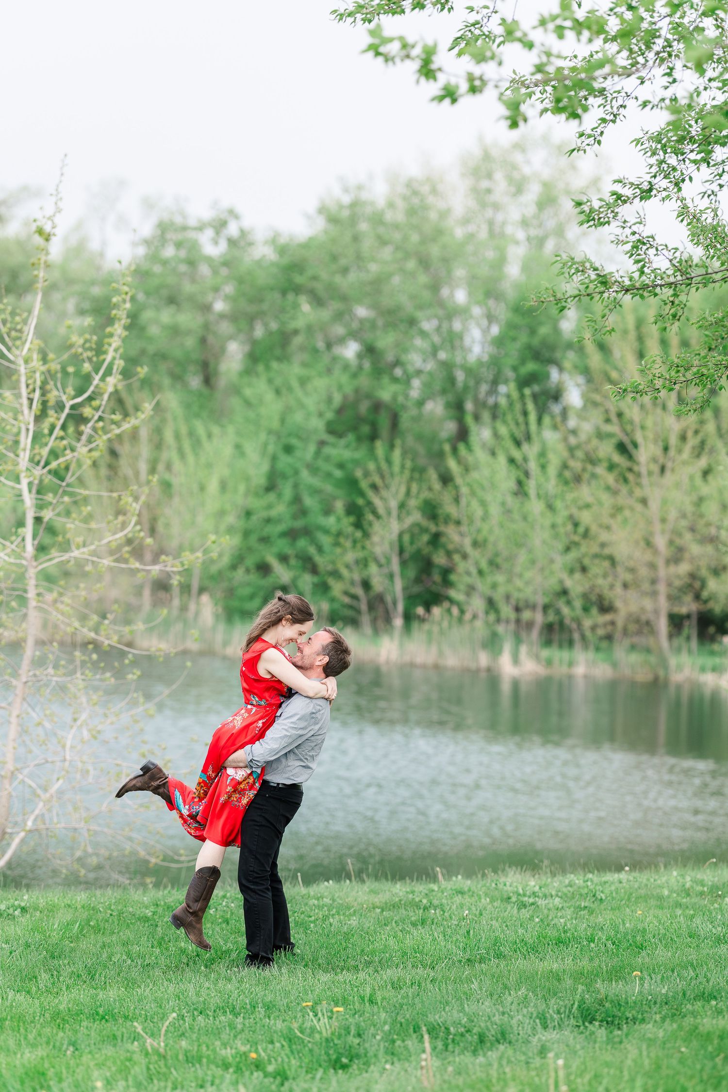 A romantic lift pose captured against a peaceful lake backdrop in springtime.