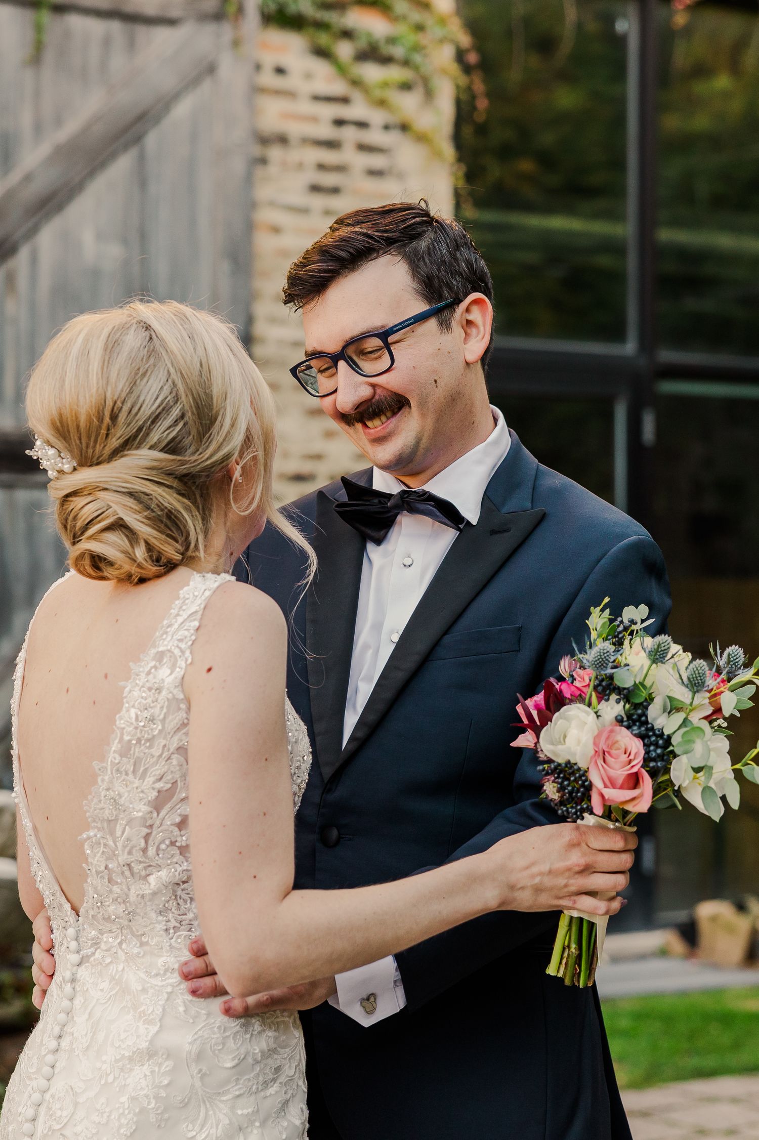 Joyful wedding couple sharing intimate moment with colorful bouquet in garden setting.