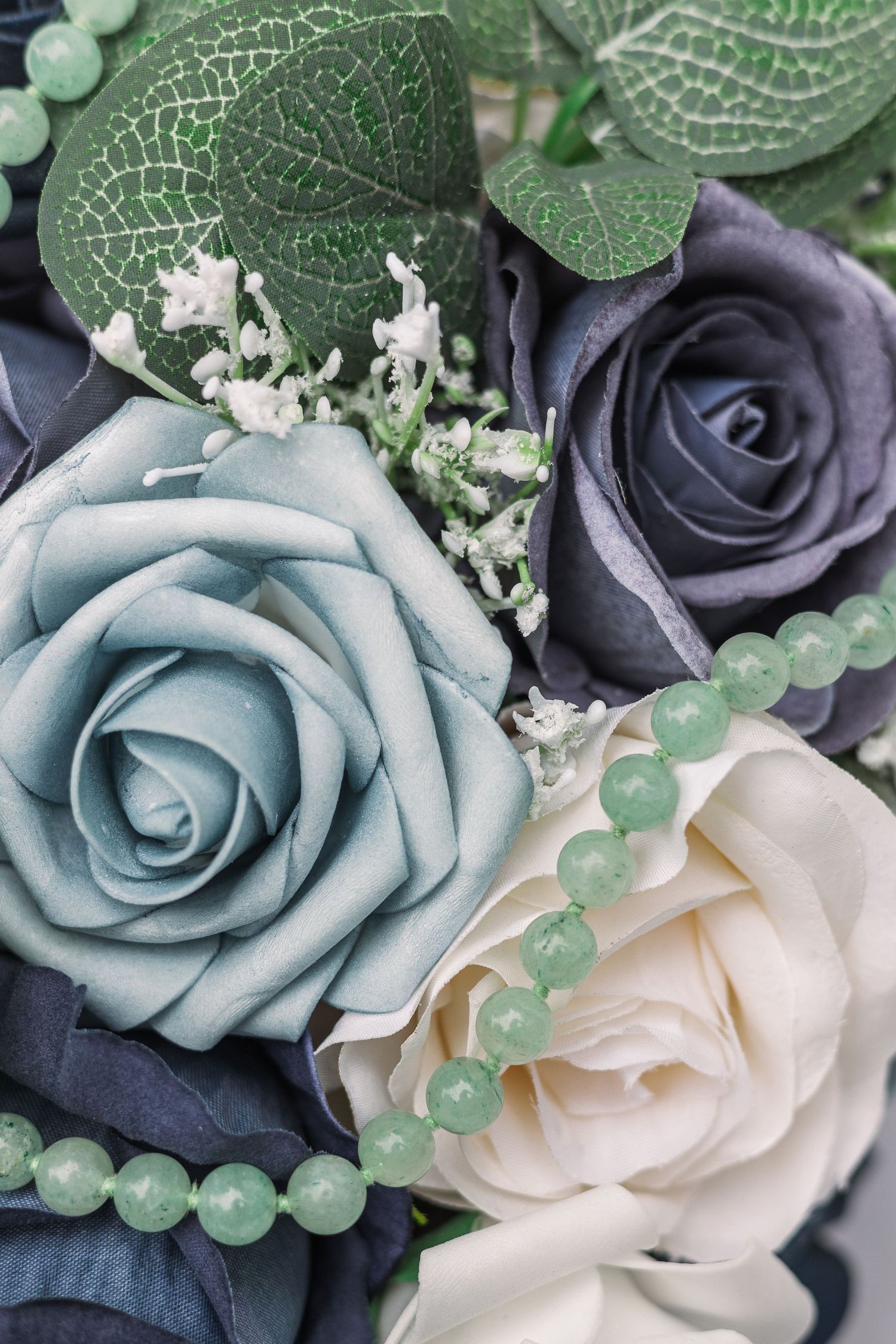 Wedding bouquet detail with blue, navy and cream roses accented with green beads.