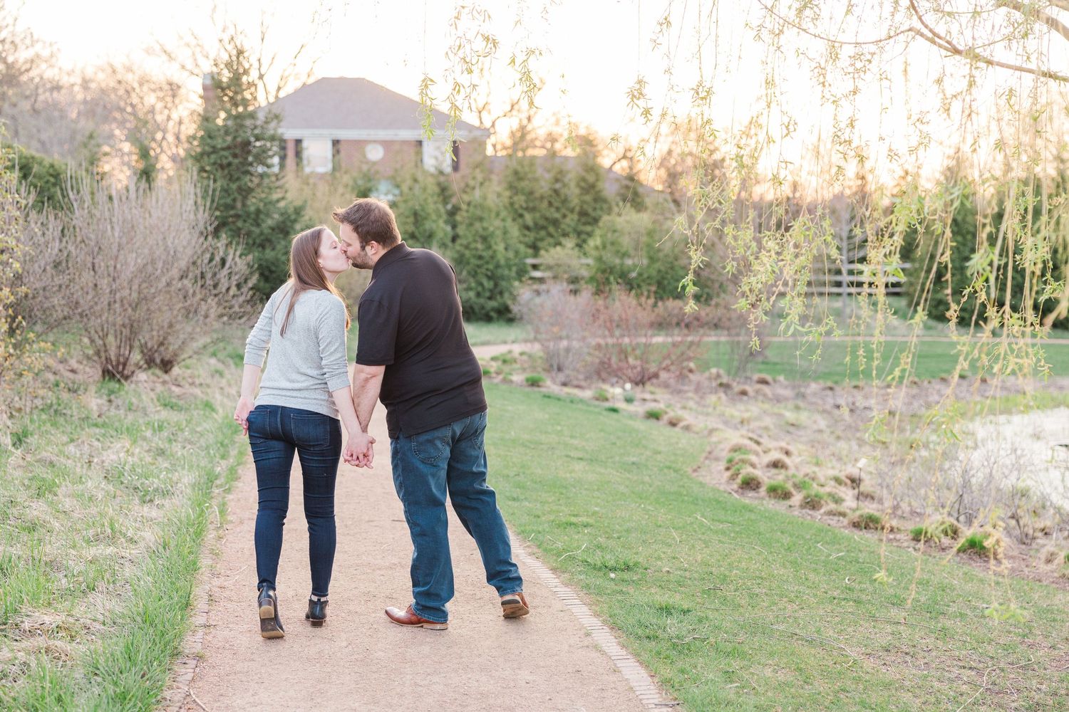 Couple walking away on garden path during golden hour surrounded by spring landscape.