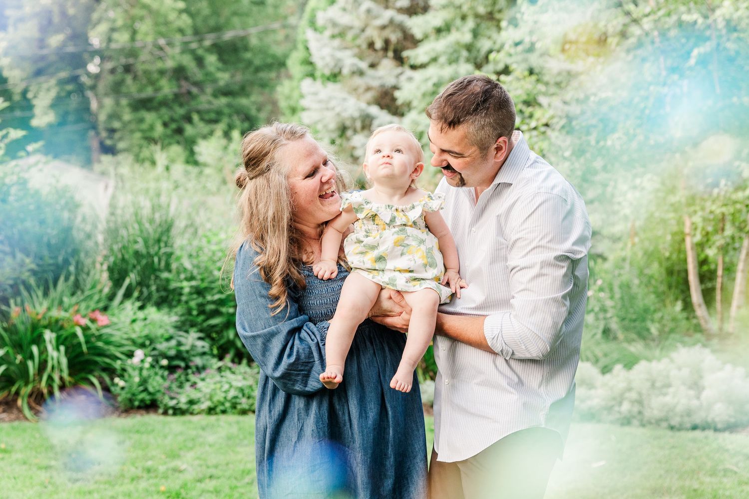 Candid family moment with genuine laughter in a sunlit garden.