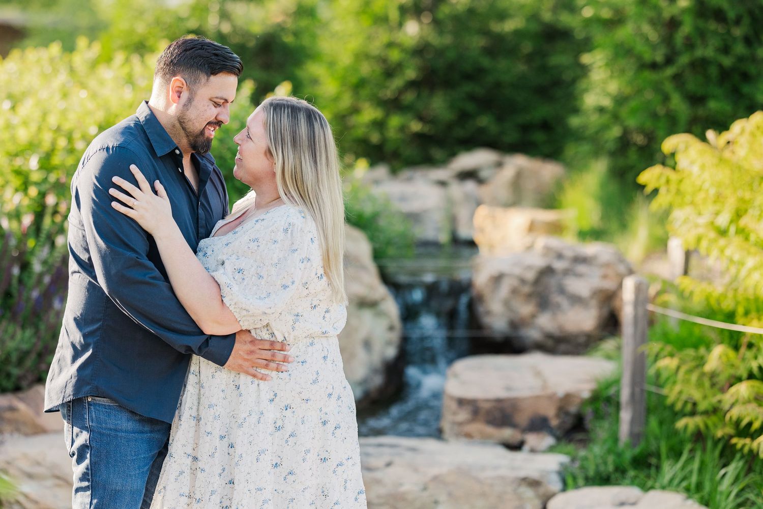 An intimate embrace shared between a couple in front of a decorative garden waterfall.