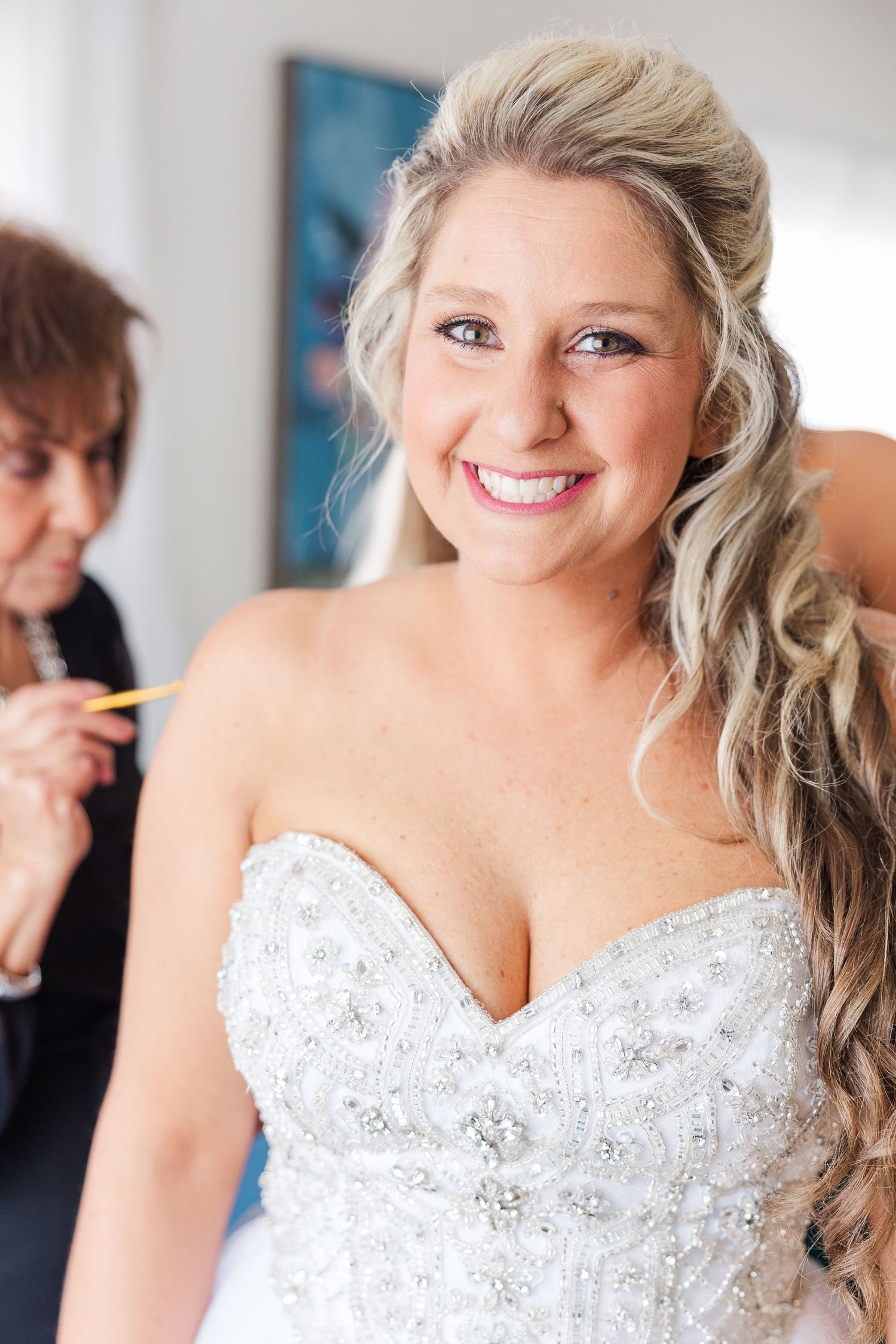 A stunning wedding dress with intricate beading and sweetheart neckline being fitted in a bright room.