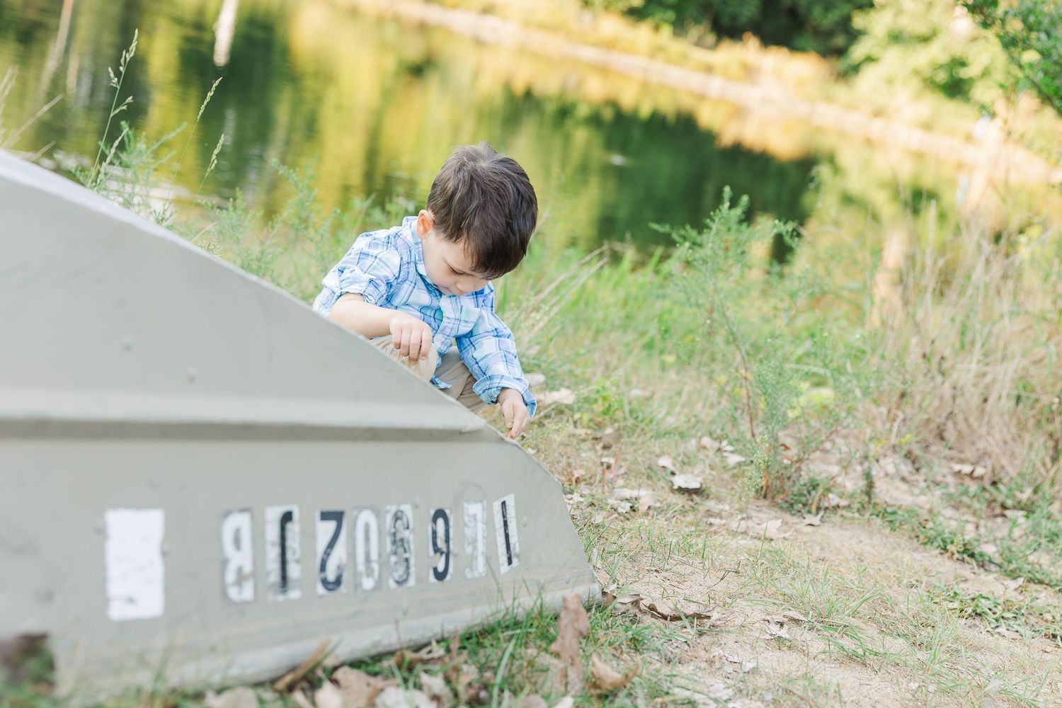 Child in blue shirt explores outdoor nature trail while hiking along wooden boardwalk in summer.Sorg family portraits at Shamrock Hills Park