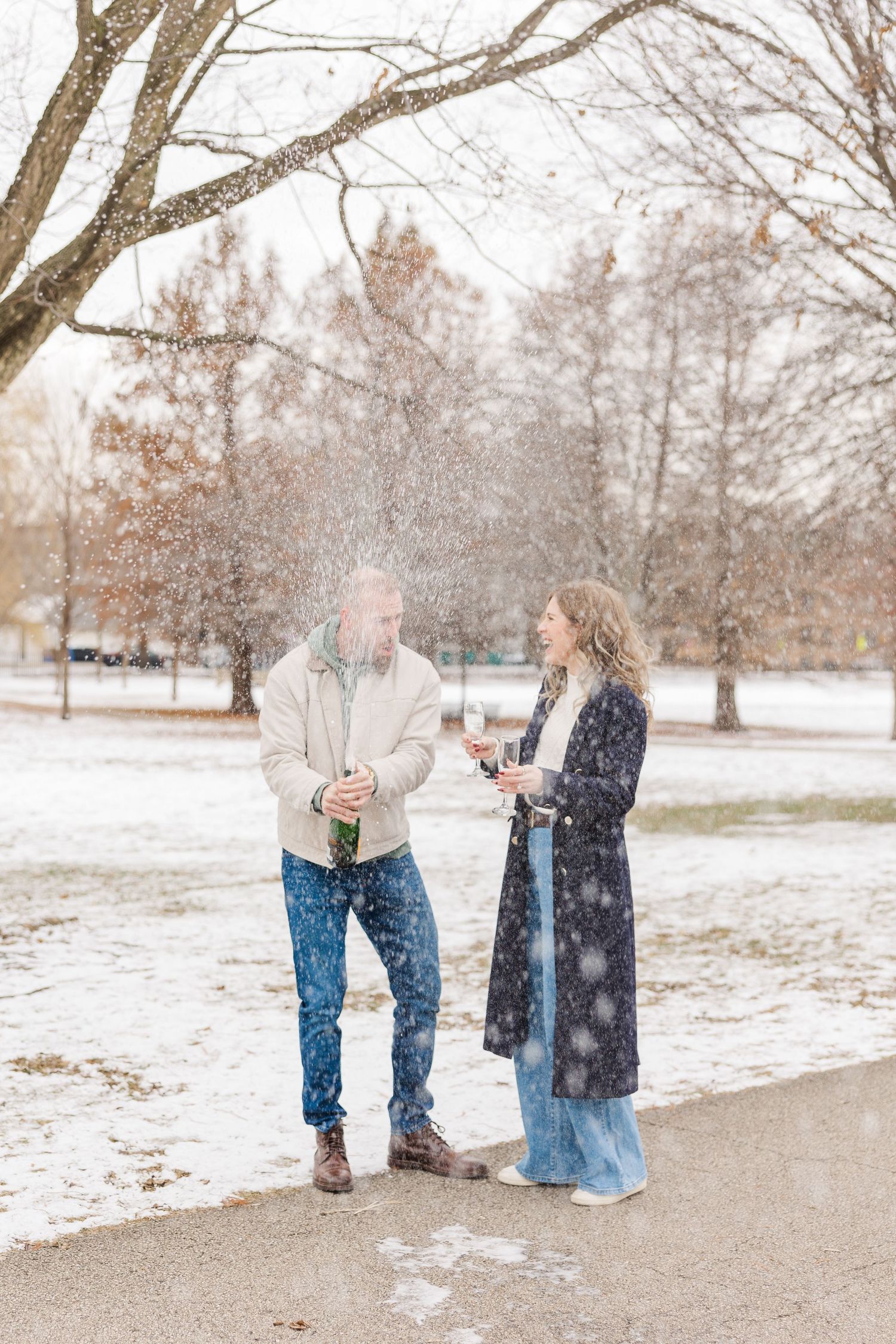 a couple pops champagne in Winnemac Park to celebrate their engagement in Winter