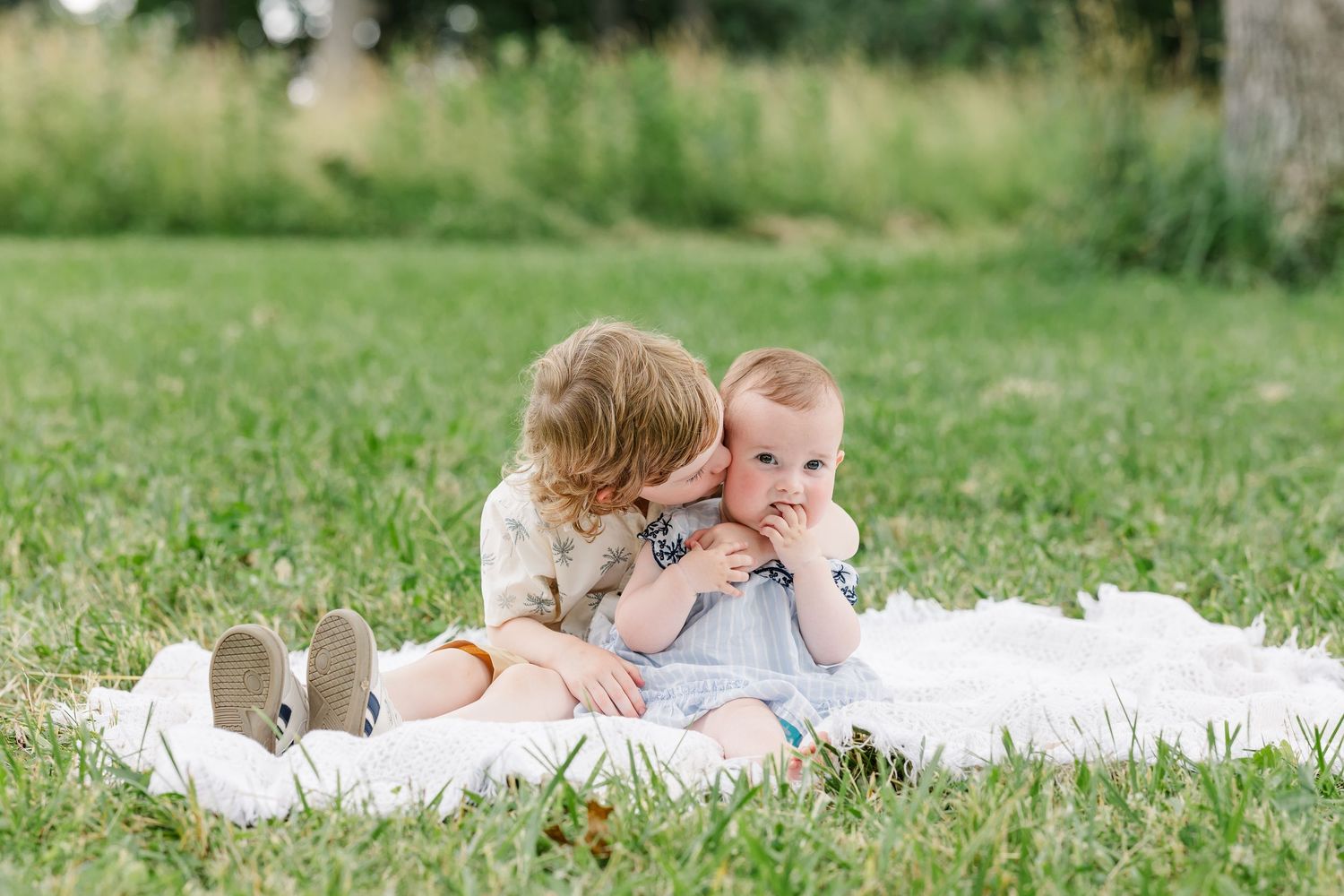 Young cousins playing together on a blanket during a summer family reunion photo session in Crystal Lake, IL.