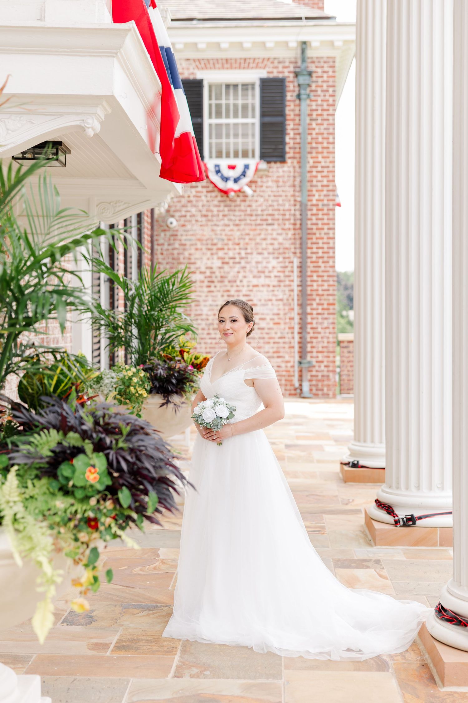 Bride posing with her bouquet and wedding dress train beneath the columns at McCormick House.