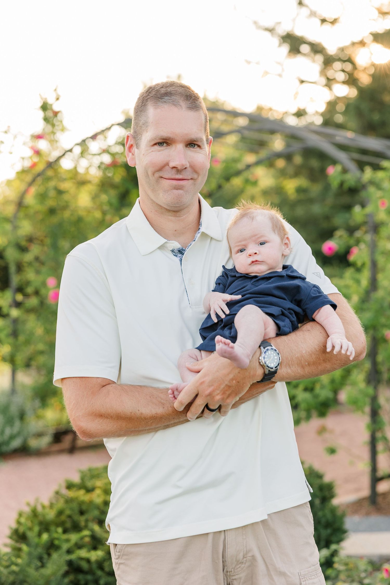 Andrew holding newborn Lincoln among the colorful gardens during their Cantigny Park family session.