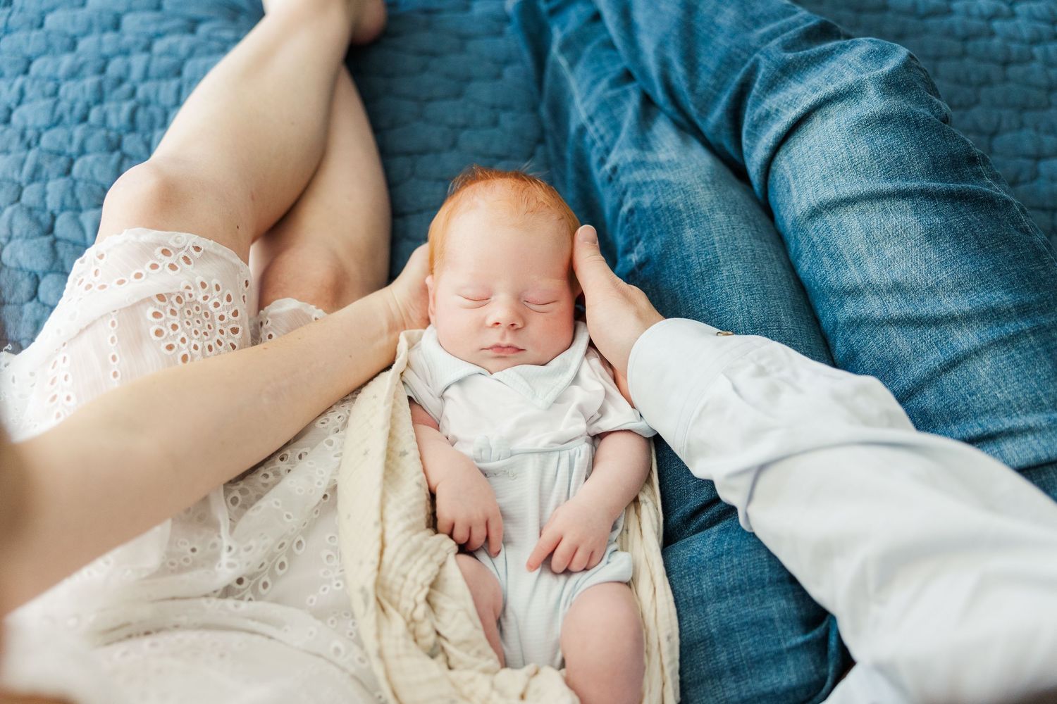 Sleeping newborn baby wrapped in a neutral blanket with parents’ hands during an in-home lifestyle newborn session in Vernon Hills IL