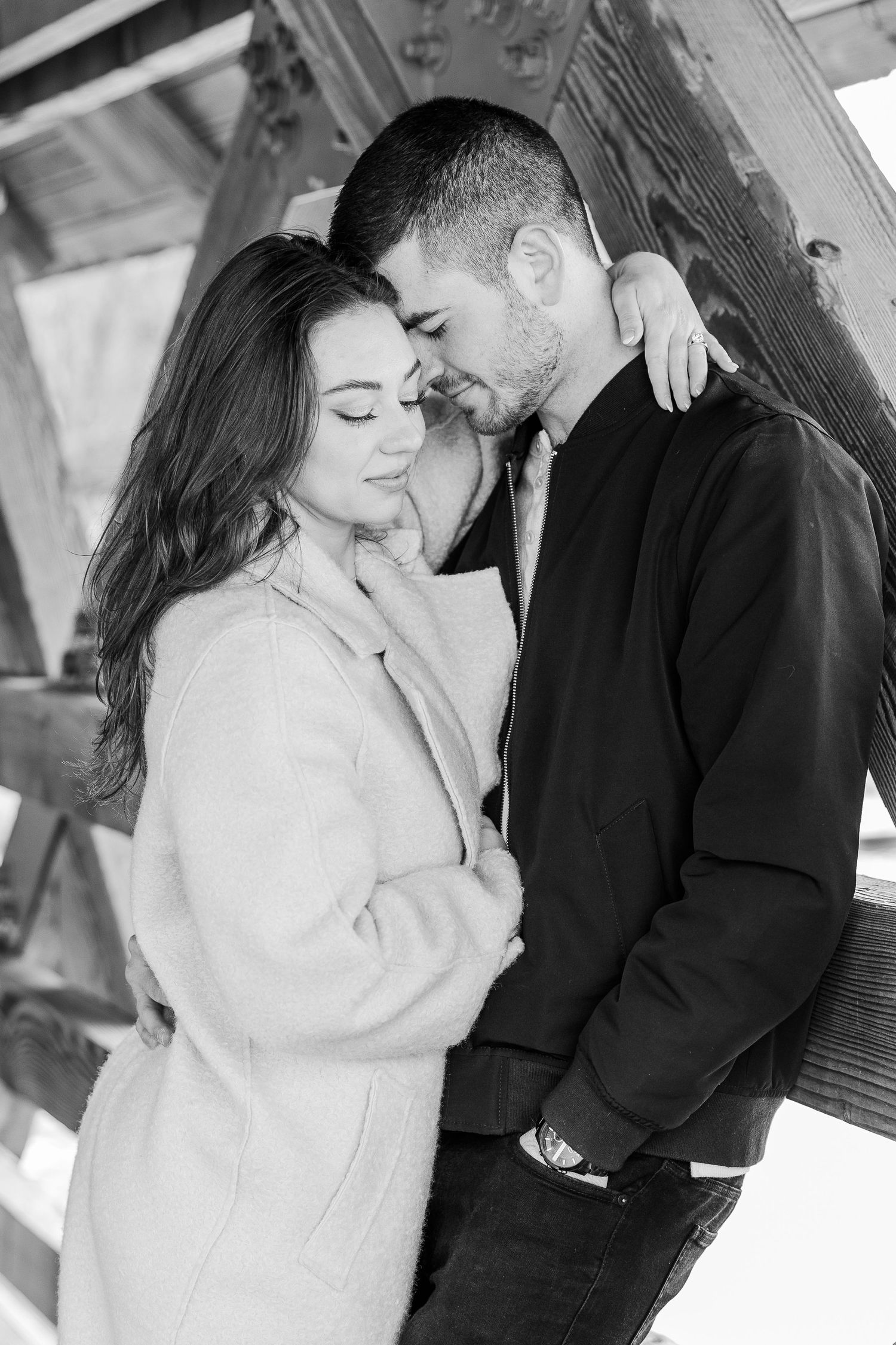 A romantic black and white photo of a couple sharing an intimate moment against a rustic wall.