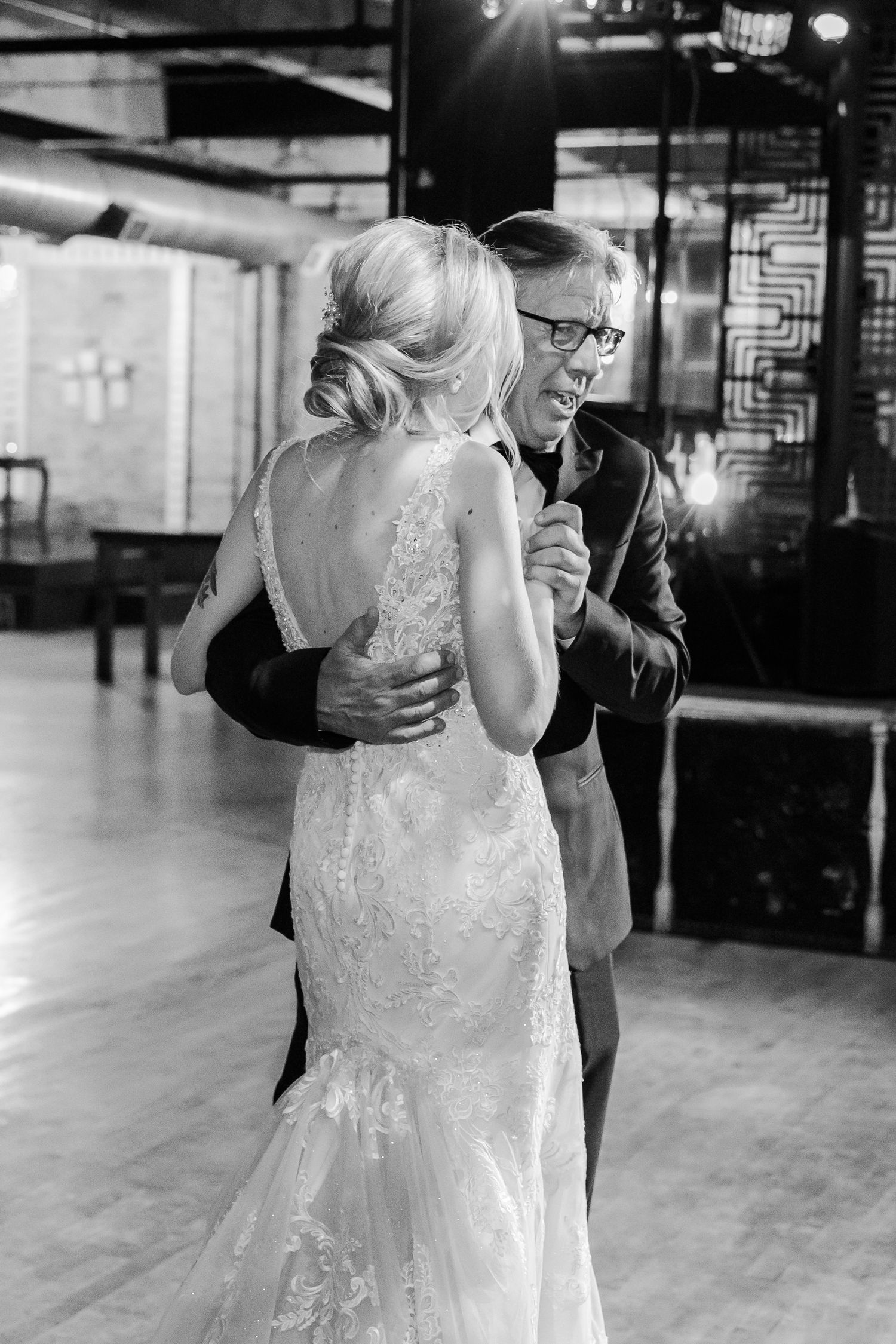 An intimate wedding dance moment captured in black and white at an industrial venue.