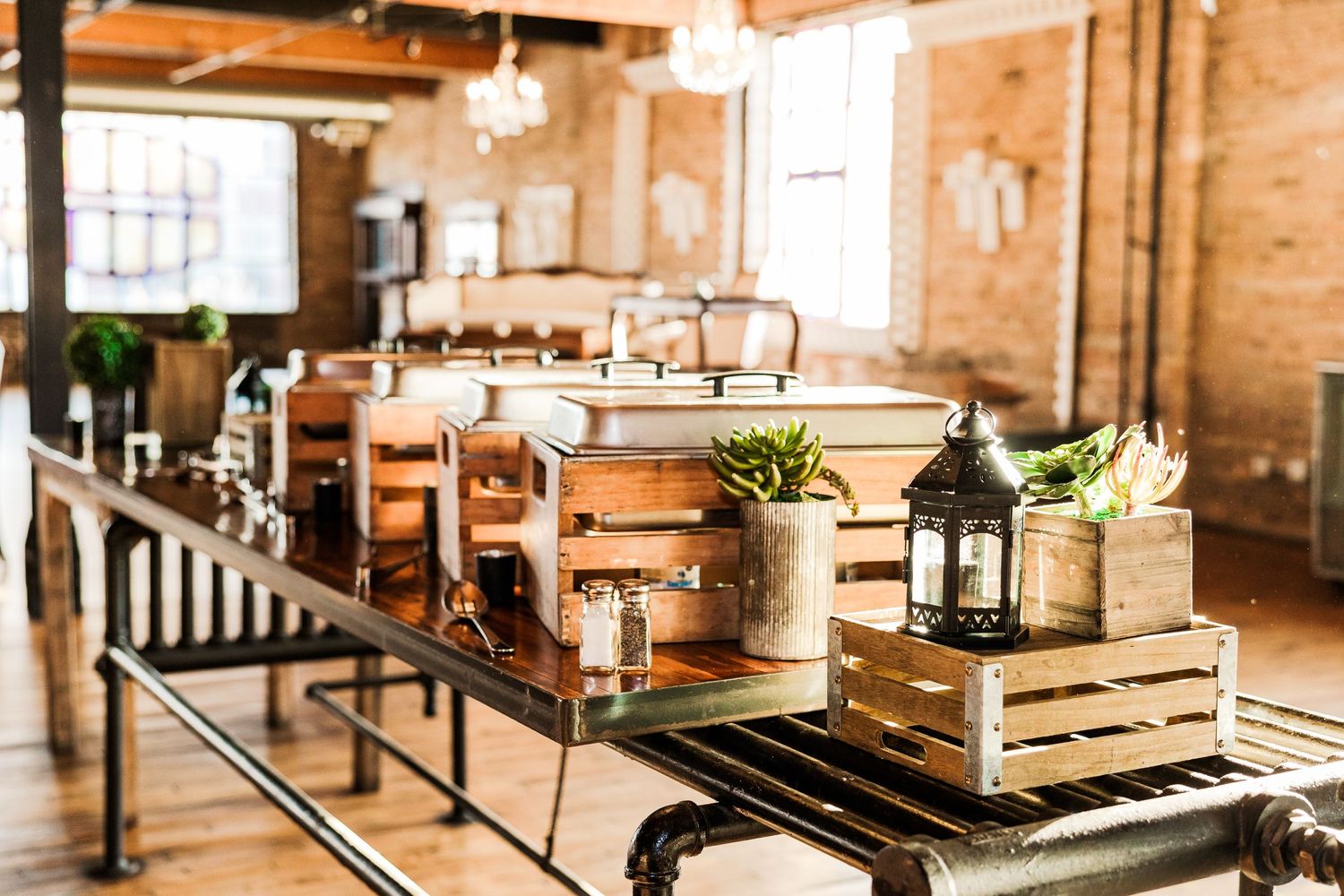 Industrial wedding venue with wooden crates, lanterns and rustic decor on long tables.