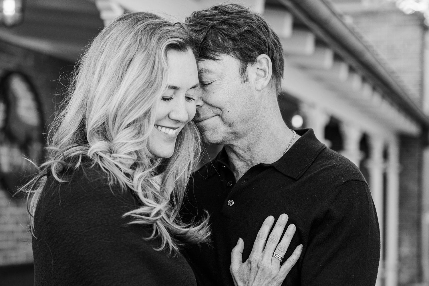 Black and white portrait of a couple sharing a joyful embrace outdoors.