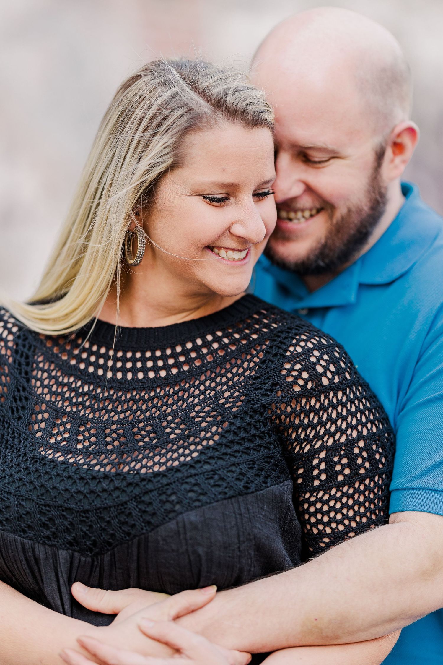 A couple shares a tender moment embracing while wearing black and blue casual attire.