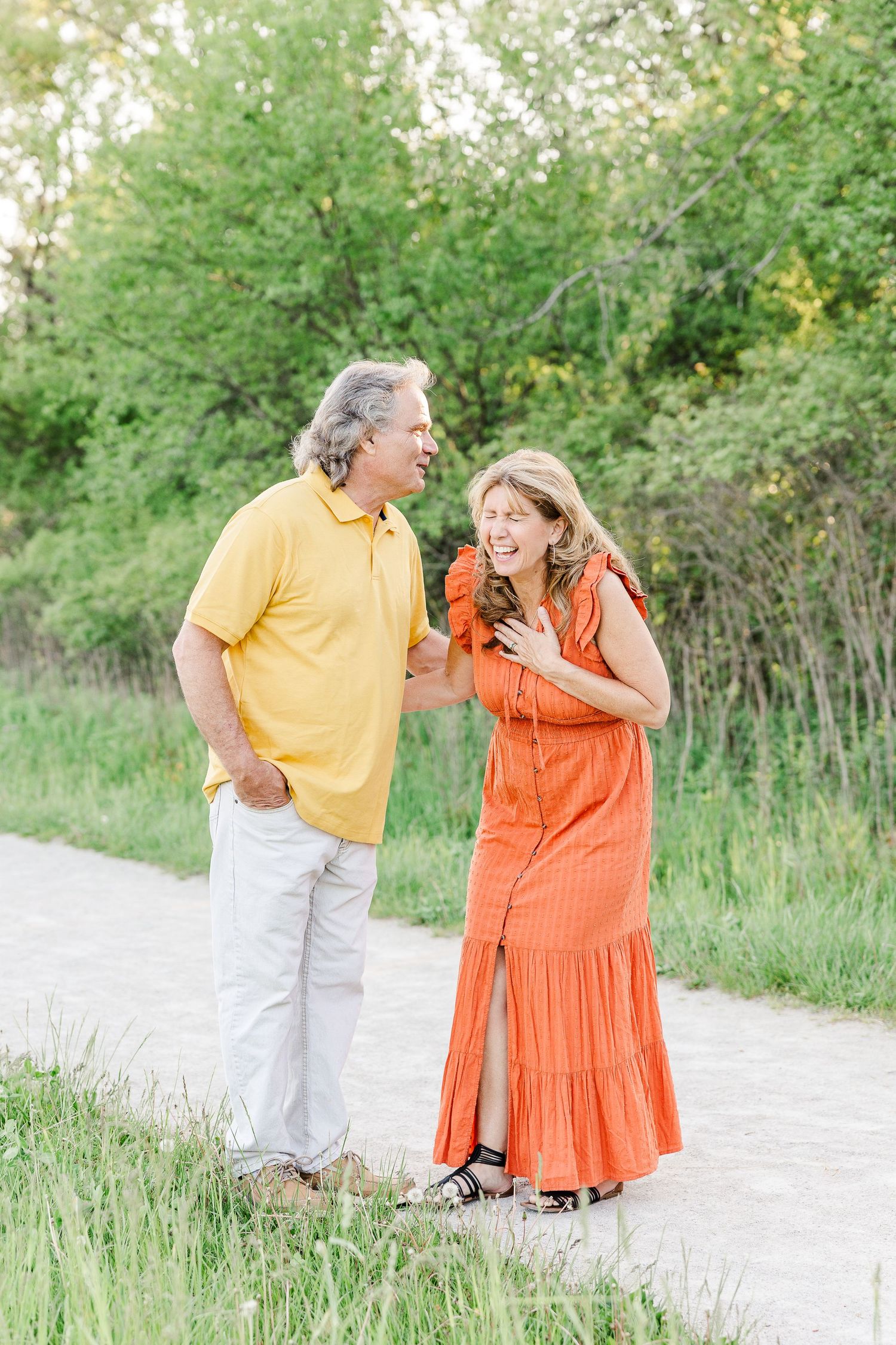 A cheerful couple sharing laughter while standing on a nature path in spring.