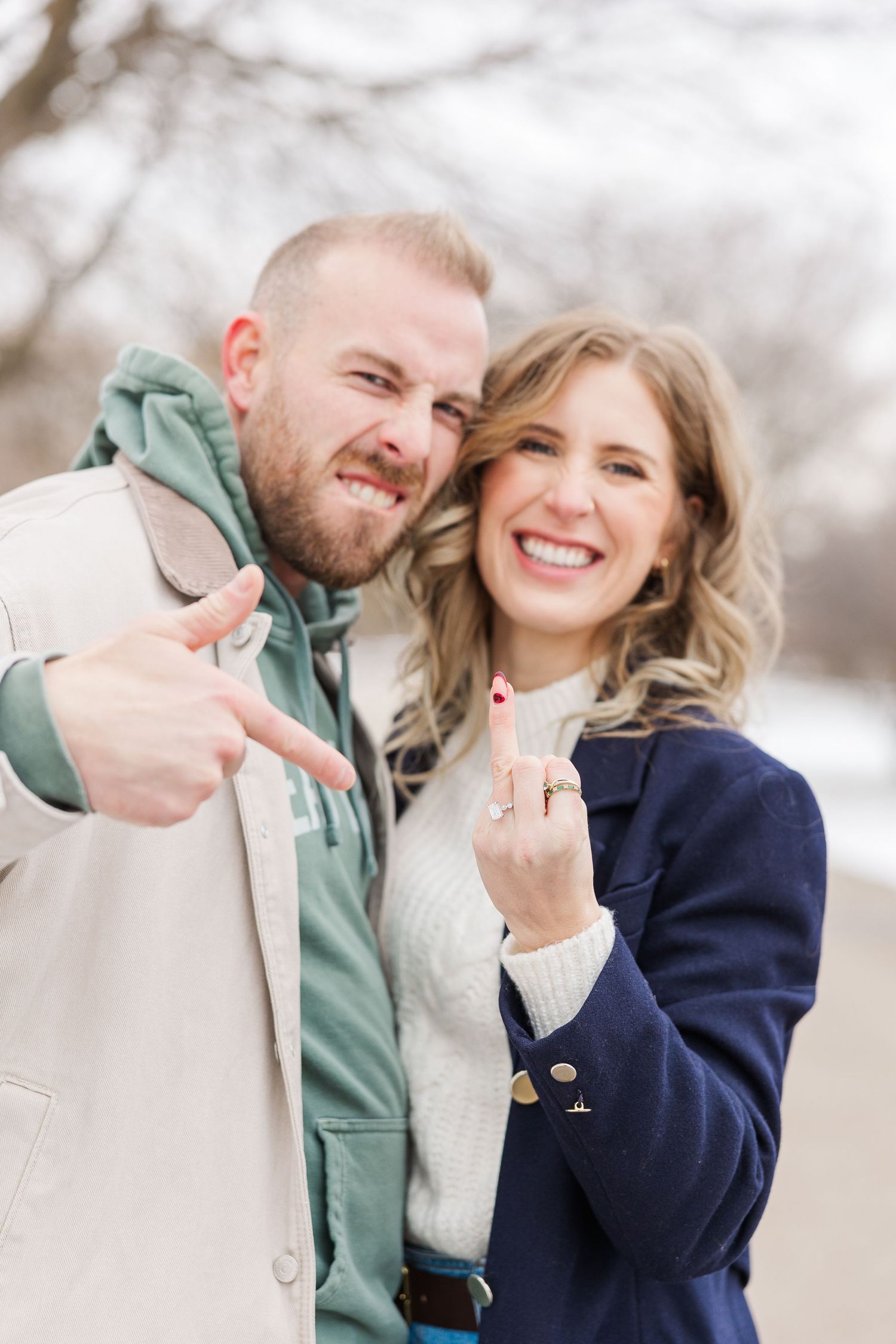 A couple showing their engagement ring while smiling during a winter engagement photo session. Winnemac Park Chicago