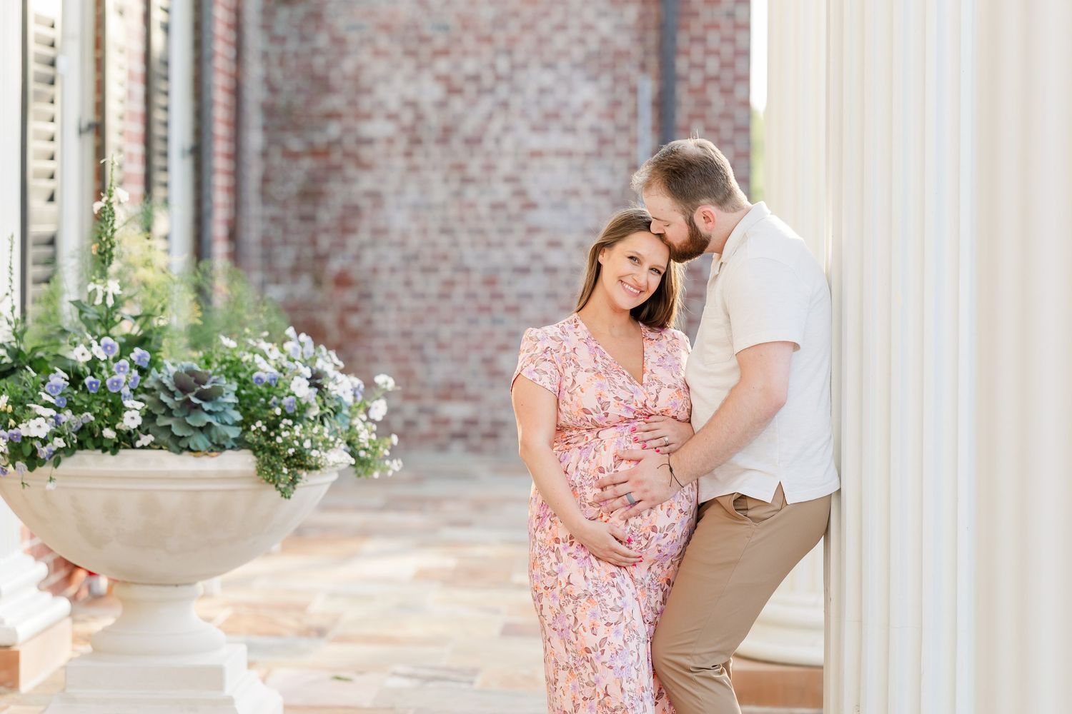 Expecting parents cuddling by brick columns during a classic Cantigny maternity session in Wheaton Illinois
