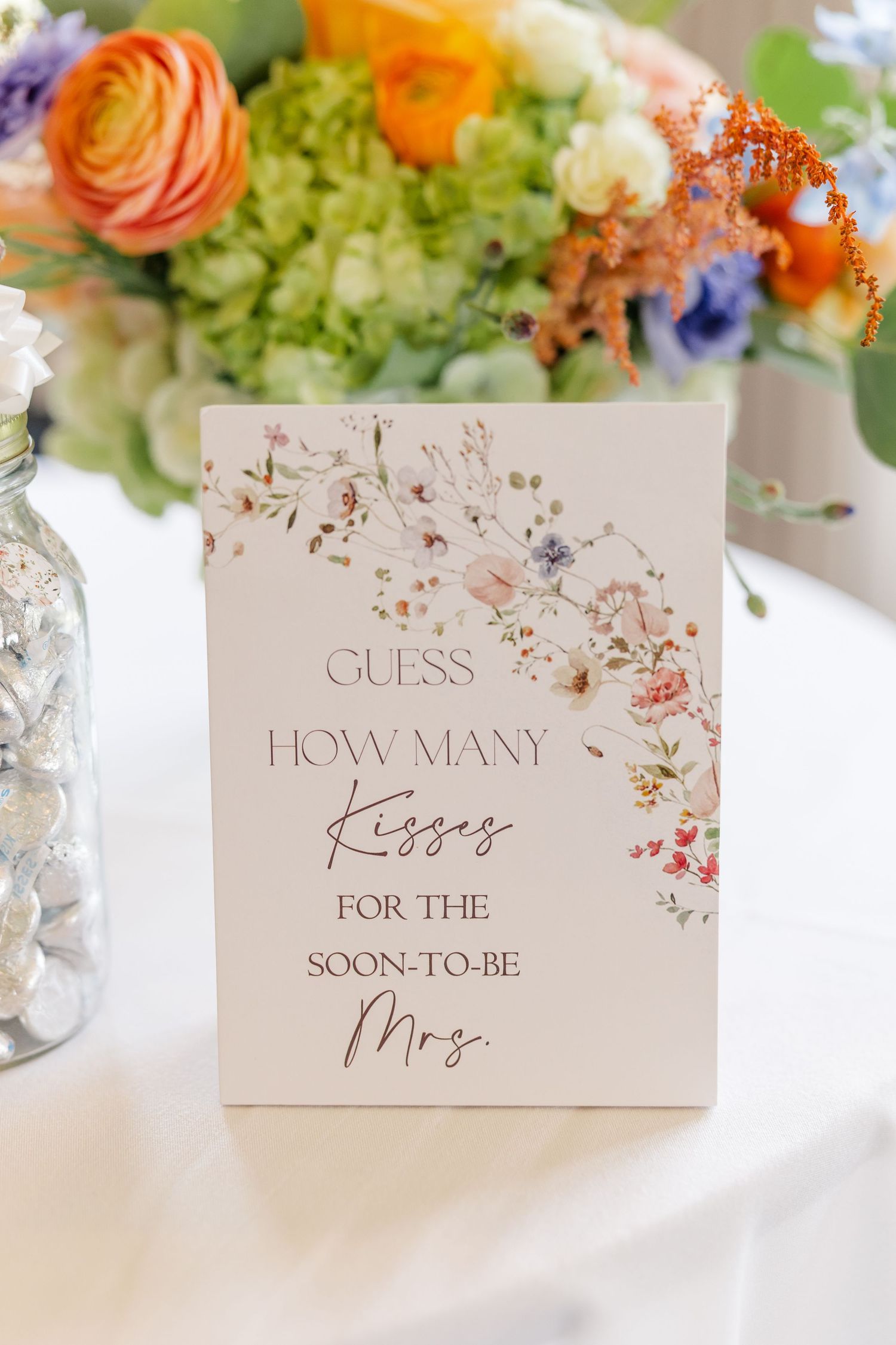 Wildflower centerpiece beside bridal shower guessing game sign