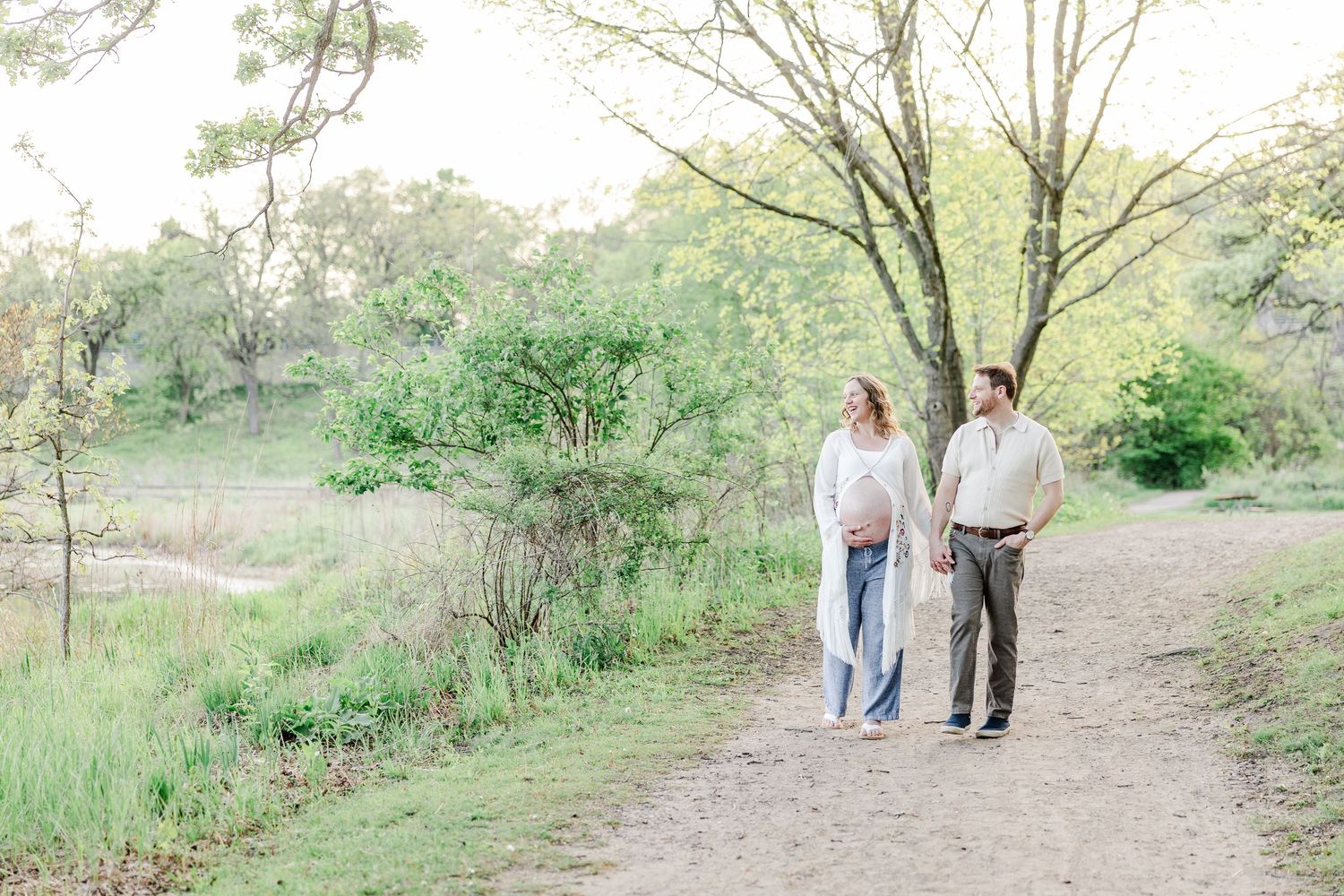 Expecting parents walking along a trail during a maternity session at Veterans Acres in Crystal Lake.