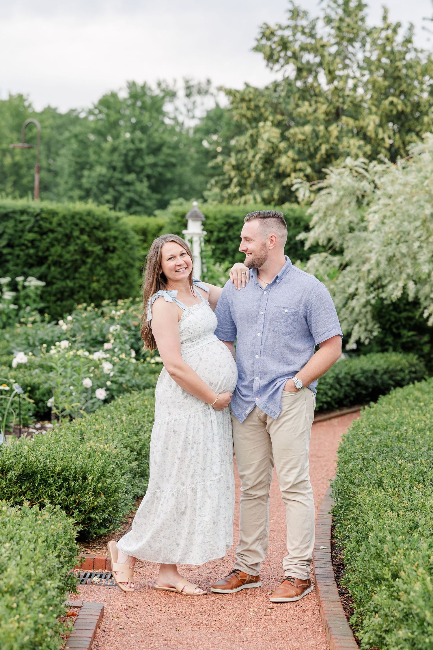 Expecting parents smiling in the summer gardens during their Cantigny maternity photos