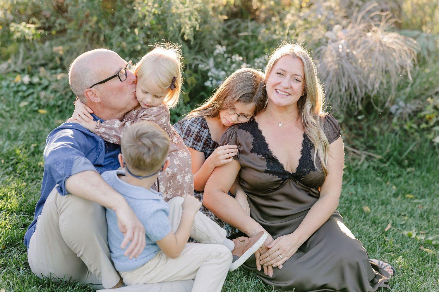 Parents cuddling their three children on a blanket during backyard family photos in St. Charles, IL.
