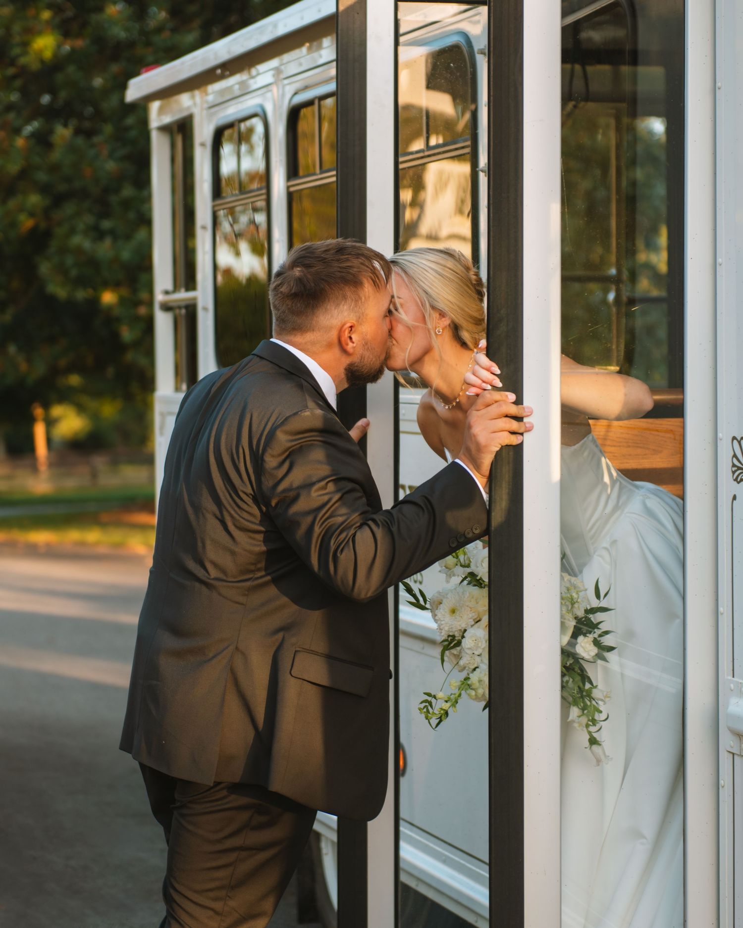 Bride and groom kissing through a window during a candid and intimate wedding portrait.
